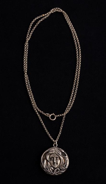 Art Nouveau Sterling Locket: Sterling marked Art Nouveau locket of woman with flower on front and monogrammed on reverse, slight bends to inside frame, approx 1.5" diam, and unmarked solo style chain.