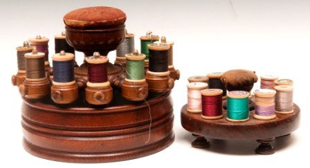 Sewing Thread Holders: Two sewing thread holders, one on round base, storage inside with spool turn and pin cushion; one footed spool holder with pin cushion