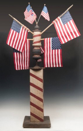 Early 20th C Barber Pole: Early folk art wind driven barber pole on a wooden base, painted square pedestal and turned topper mounted on a screw driven turned topper (flags not original) 50"h x 28"w x 28"d
