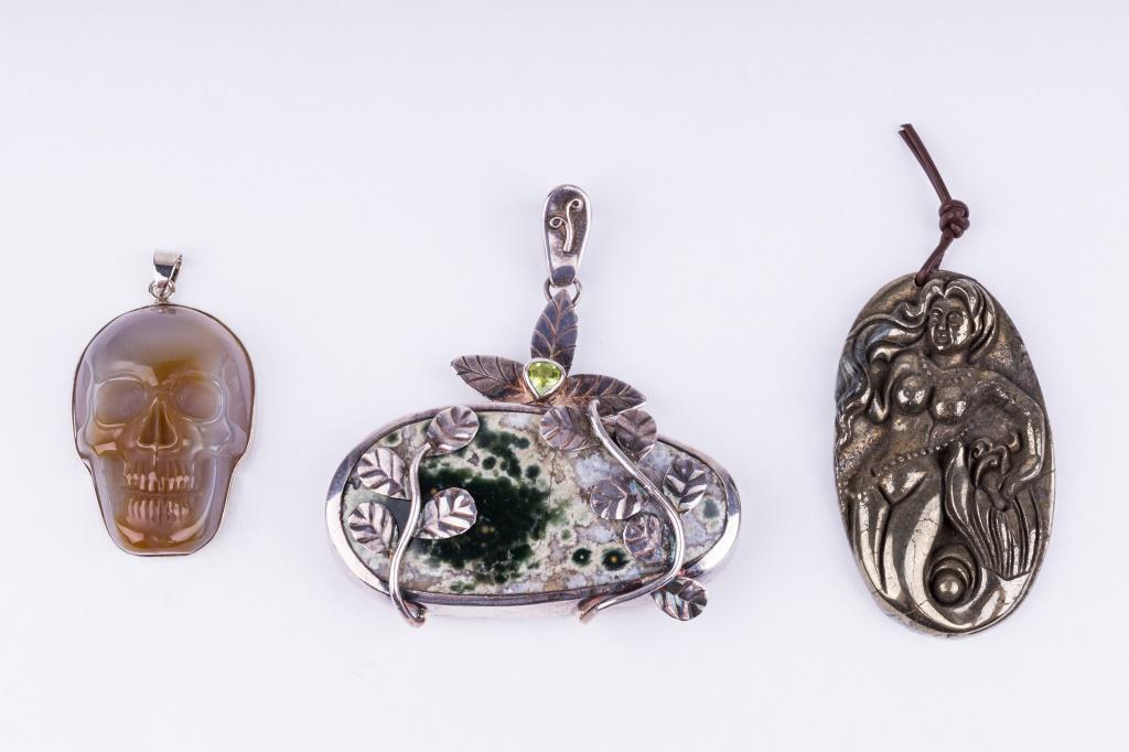 Sterling Silver Semi Precious Pendant & More: Sterling silver pendant marked 925 and signed Rehm (?) (weighs approx 1.85 ozt). It holds an agate with druzy on the back, accented by a peridot stone. 2.5" L x 2.25" W. There is also an agate skull a