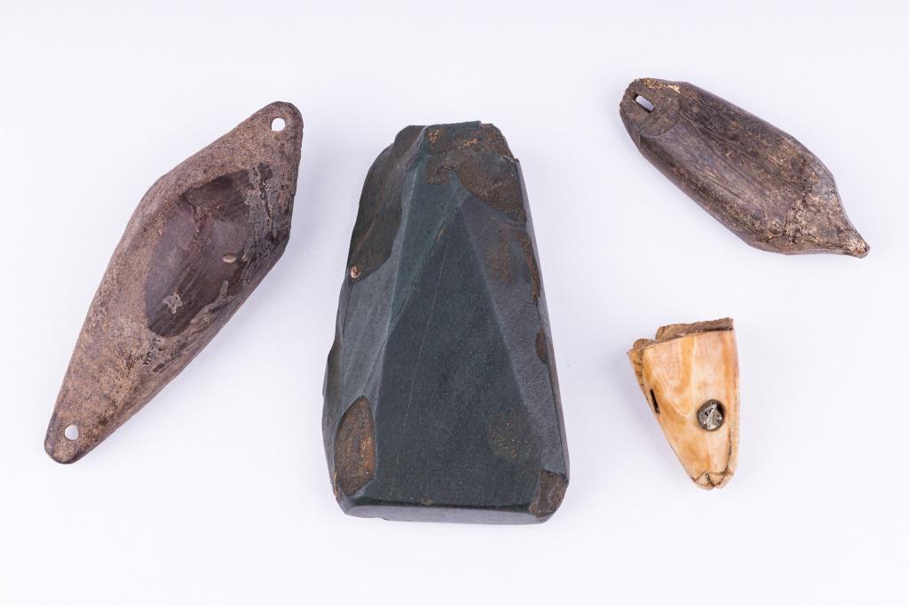 Antique Inuit Fishing & Jade Artifacts: Antique Inuit inupiaq (Inupiak) artifacts from Savoonga, Wales & Koyuk Alaska. Lot consists of two fossil walrus sinkers (largest approx 3.5"), a carved walrus fish head lure fragment with inset magne