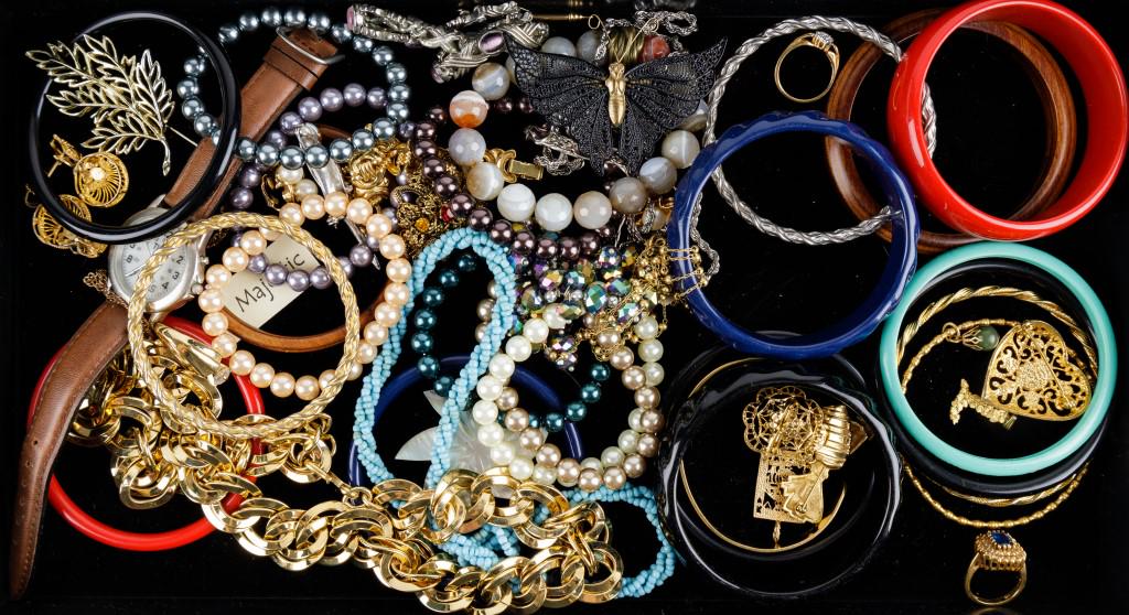 Costume Jewelry Assortment: Lot includes several plastic, wooden and gold tone bangles. Pearl stretch bracelets, gold tone necklaces, rings, a watch, and various other pieces.