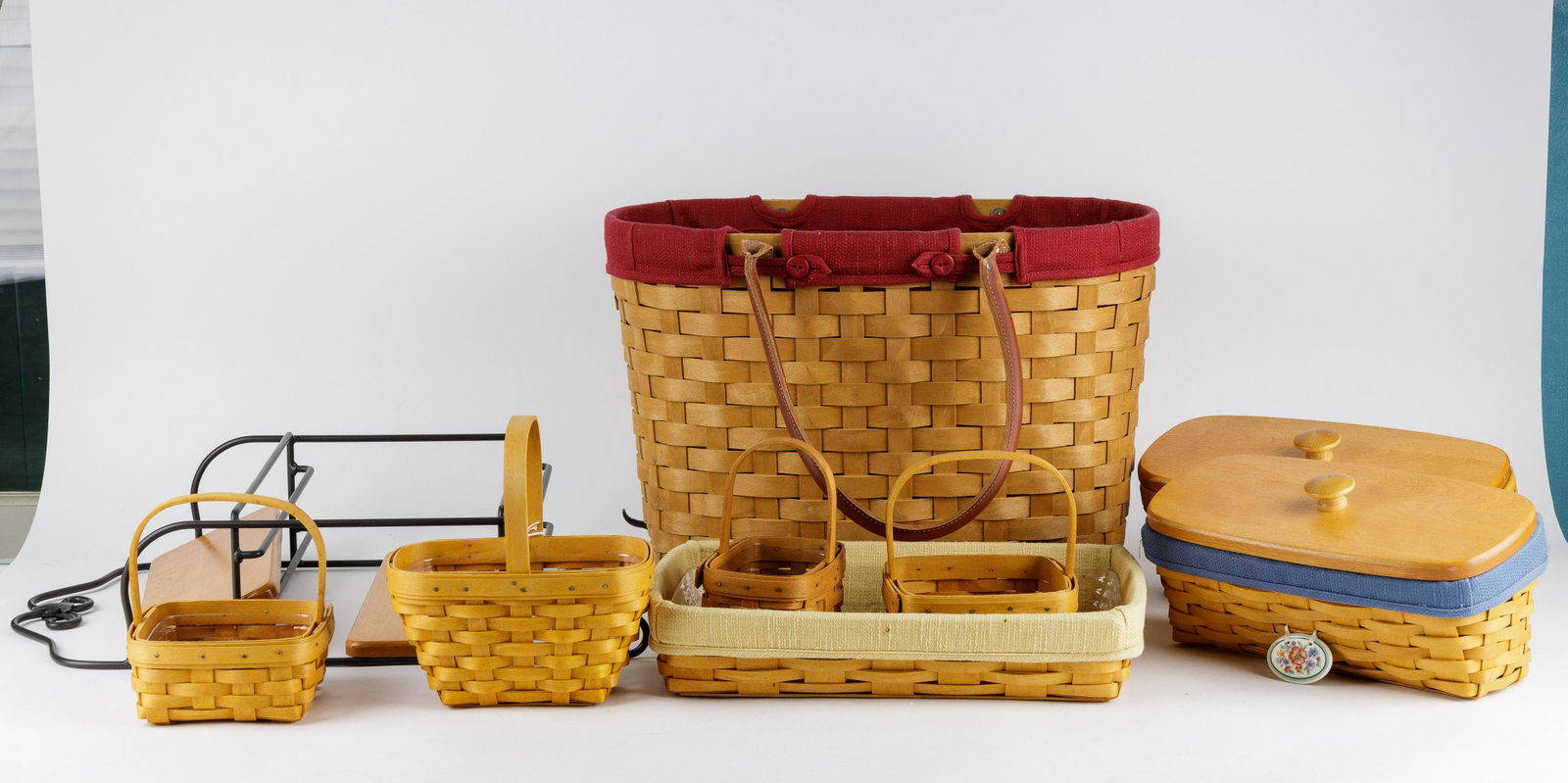Longaberger Baskets: Lot of 8 Longaberger including tote basket with liner and leather handles, a tray with liner and protector, wall rack and more baskets with protectors.