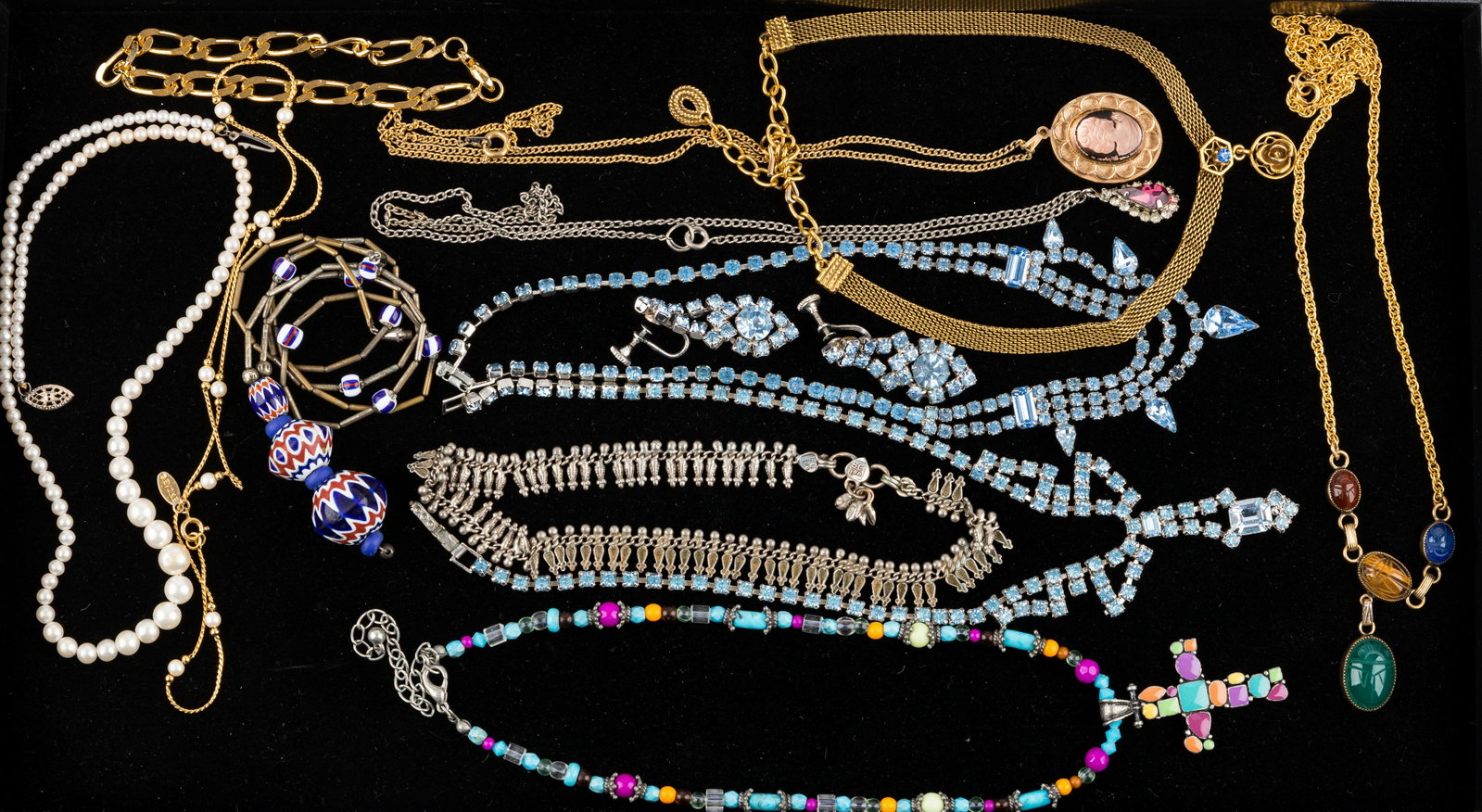 Costume Jewelry (13): 13 pieces of costume jewelry including two blue rhinestone necklaces with one pair of matching earrings, scarab beetle necklace, enamel on metal and bead cross, two faux pearl, glass cameo, trade bead