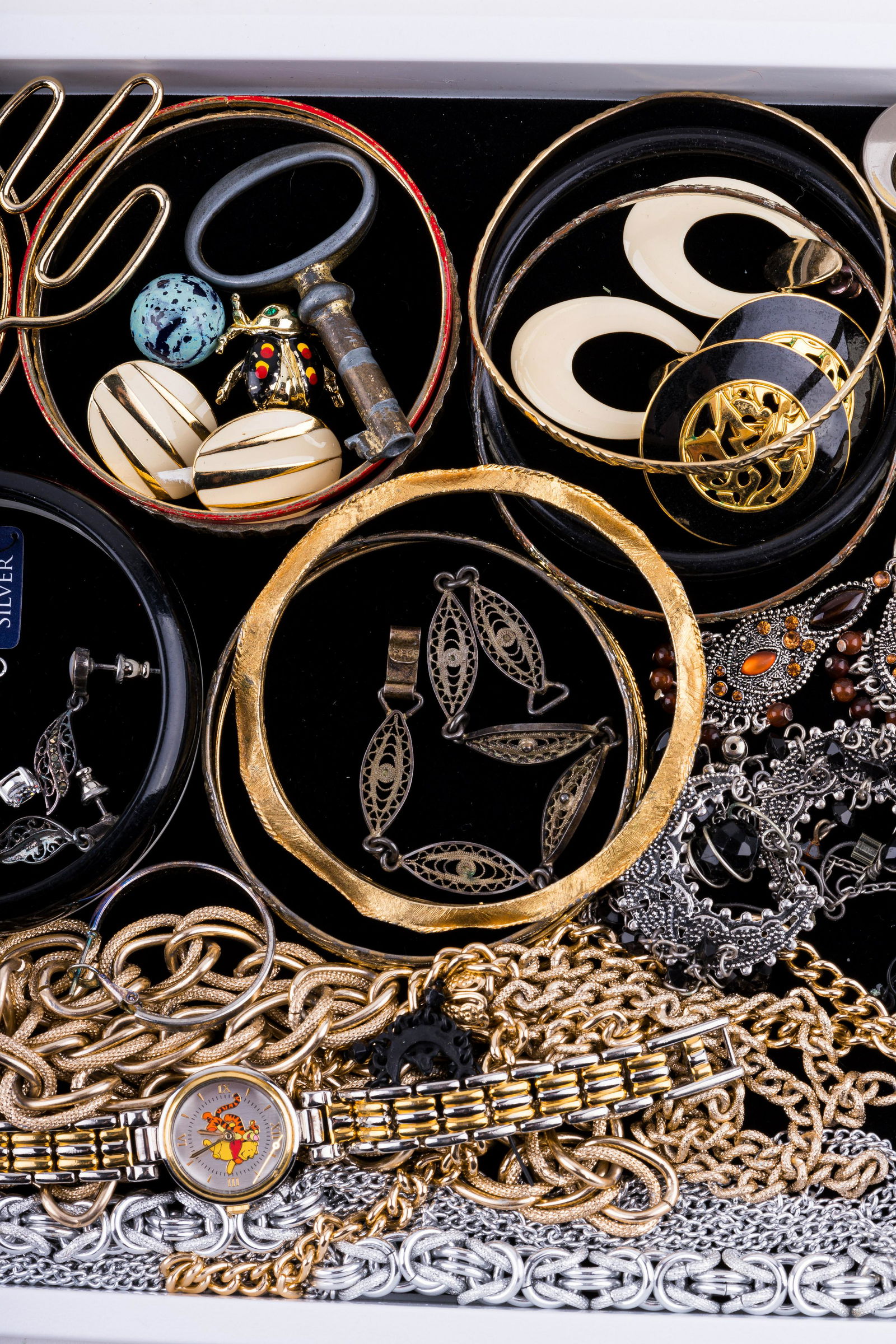 Vintage Costume Jewelry: Lot of 40+ pieces of jewelry include necklaces, bangles, earrings, watches, brooch, keys, pendants and more. Sterling filigree bracelet marked JBJ. Watches include Winnie the Pooh Disney. See photos.