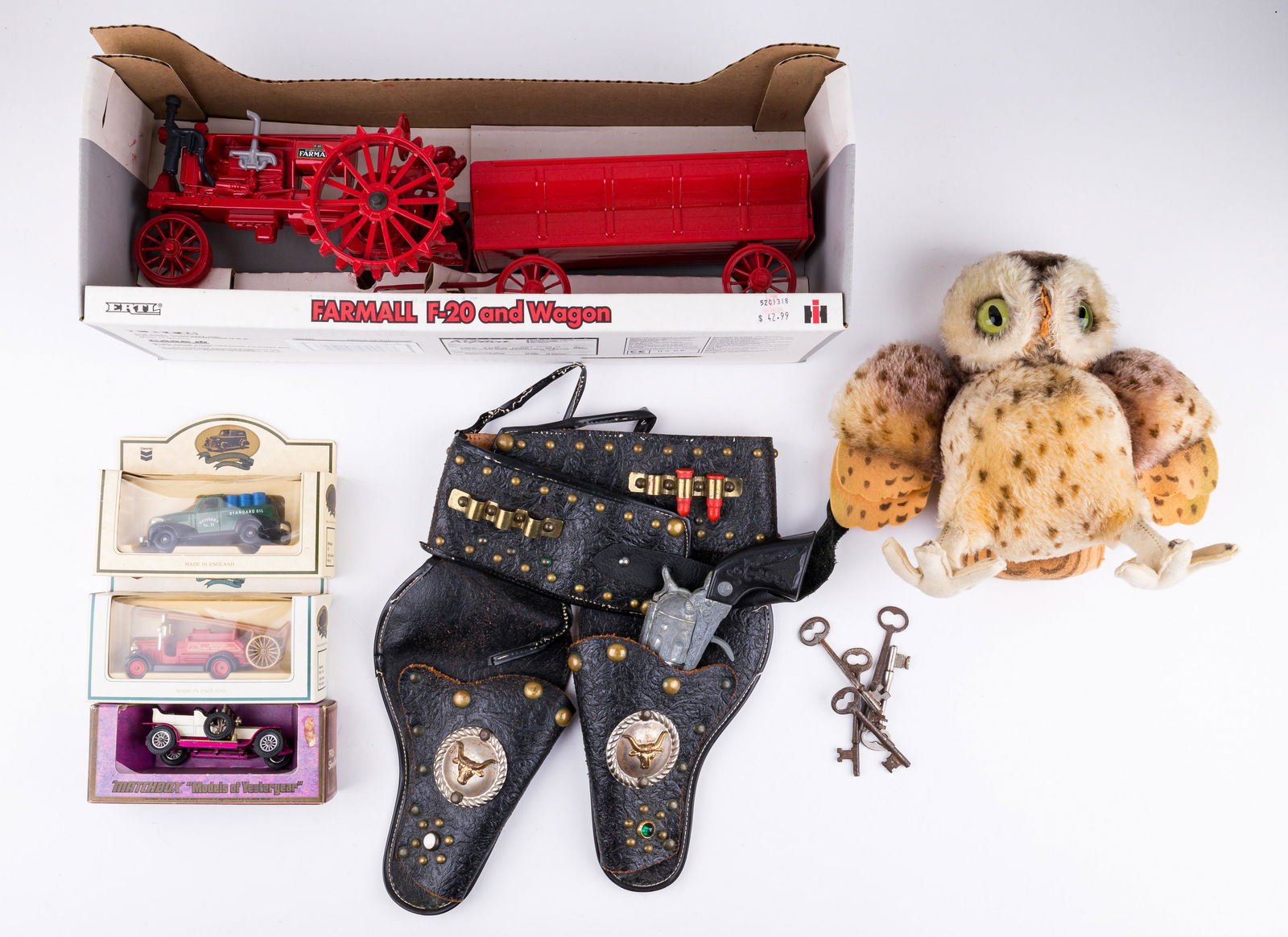 Vintage Toys: Lot includes Ertl Farmall tractor in original box, three die cast cars (in original boxes) including a Matchbox "models of yesteryear", antique owl and toy guns. One toy gun is missing, the owl is mis