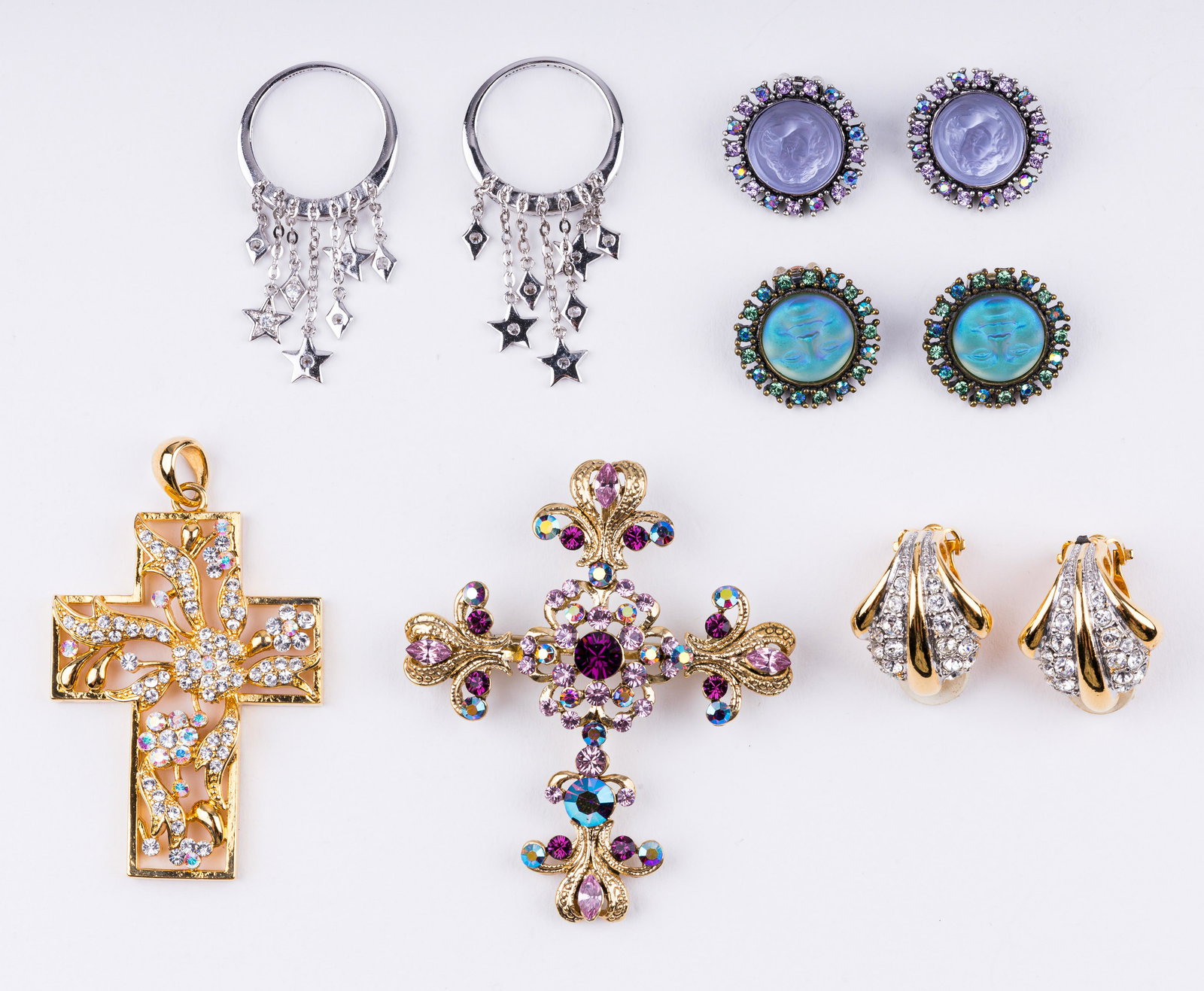 Kirks Folly Earrings & Pendants: Lot of four sets of earrings and two pendants. Earrings include moon faces, angels, stars. There are two religious cross pendants (one is a brooch pendant). All stones for glass. See photos.
