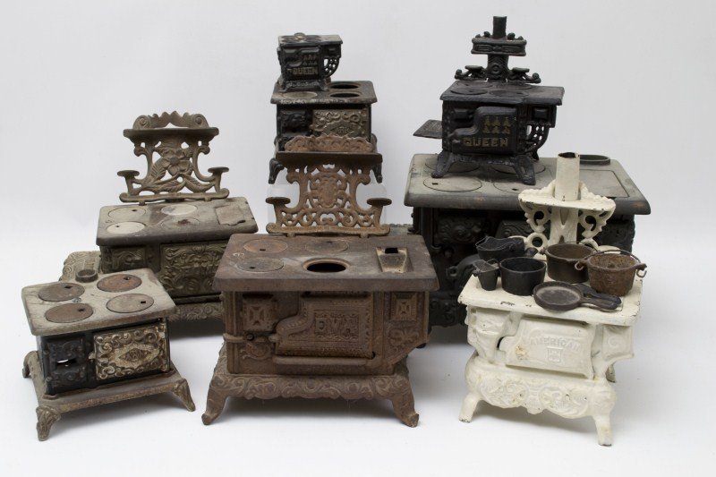 Miniature Wood Stoves: Seven miniature cast iron wood stoves including an American, two Ark, a Queen, a Royal and an Eva along with some accessories; all but the small Queen are incomplete