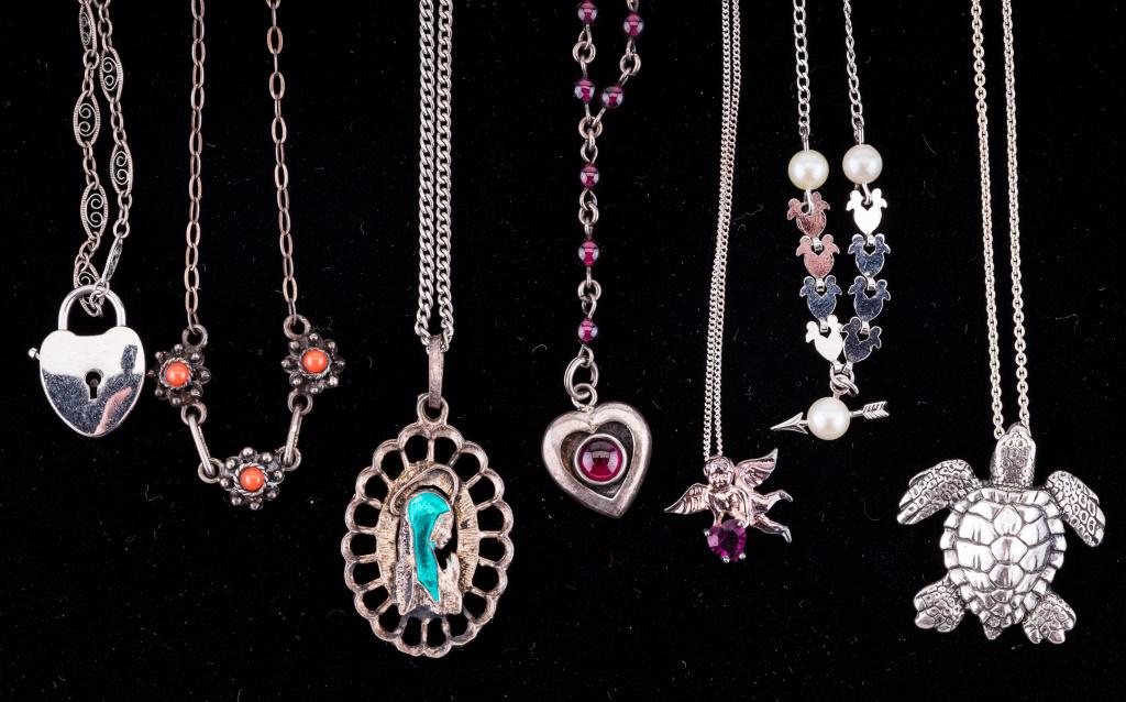 Sterling Silver Necklaces: Lot of seven sterling silver necklaces including one with real pearls, heart shaped is garnet, real coral and more. Turtle necklace is longest, measuring 23" L.