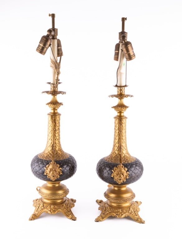 Pair of French Imari Lamps w/ Bronze + Brass: A pair of French Imari lamps with bronze and brass, measuring approx. 26.5" high. Lamps are colored black and gold, and each lamp has two golden lion heads raised from each side of lamp. Lamps are in 
