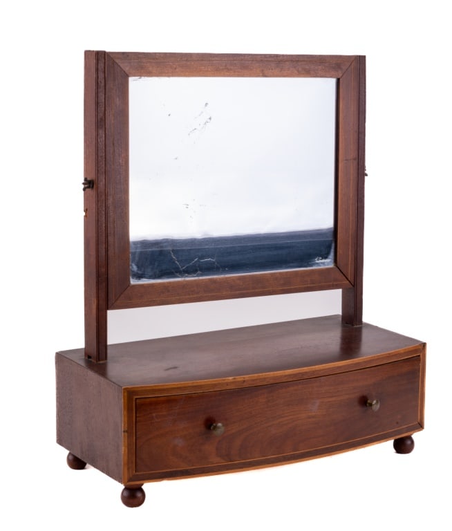 Dresser Top Antique Shave Mirror: Antique footed shaving mirror with drawer made of veneer wood with wood inlay along the front drawer. Has a leaded mirror that tilts. Measures approx 16" H x 14" L x 7" D. Name possibly "Shields" is w