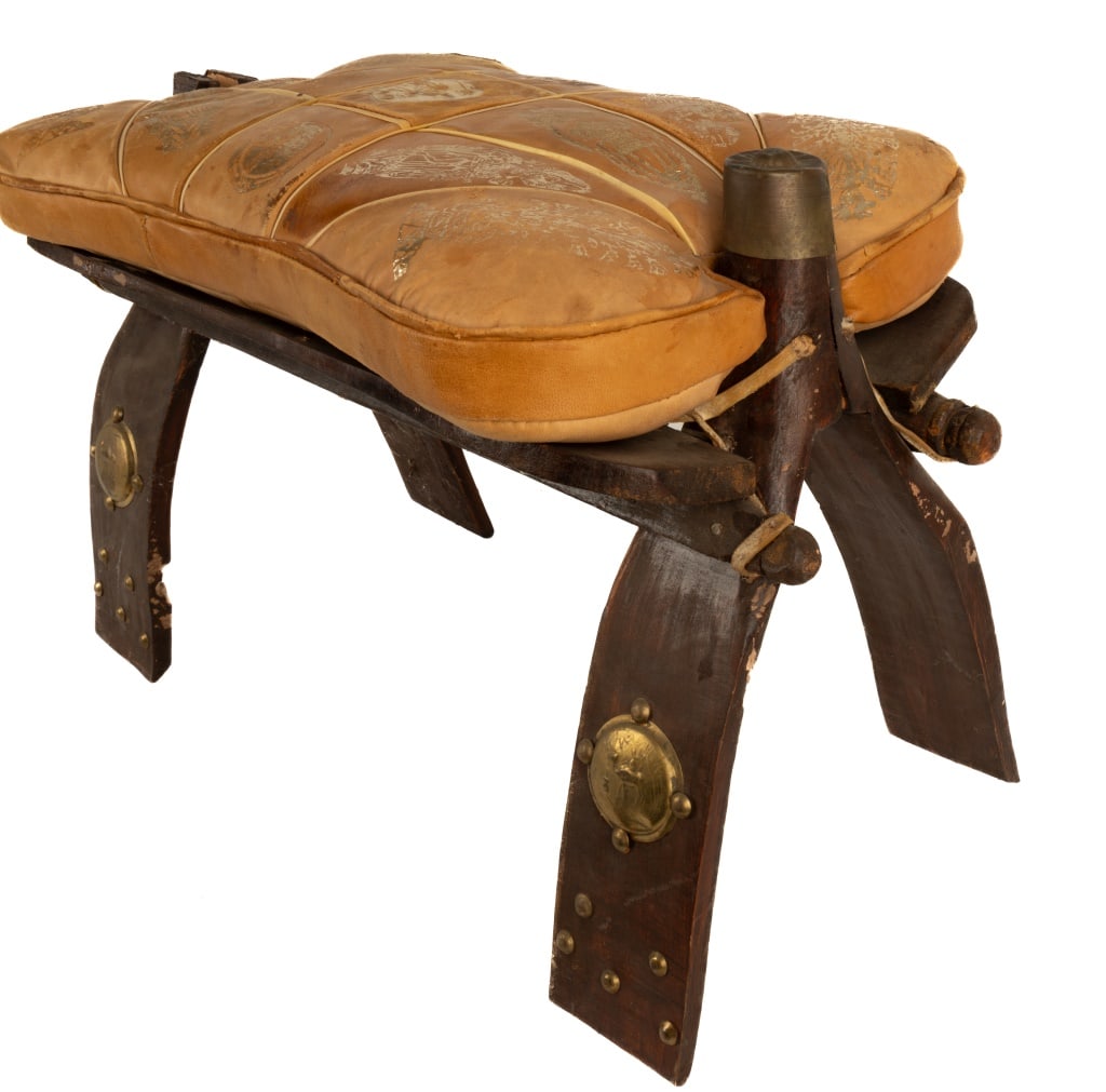 Vintage Camel Saddle: Vintage camel saddle with leather seat, brass mounts on wood. Missing one brass finial on top of one arm. Measures approx 15" H x 23" D x 12" W. One leg has some wood loss.