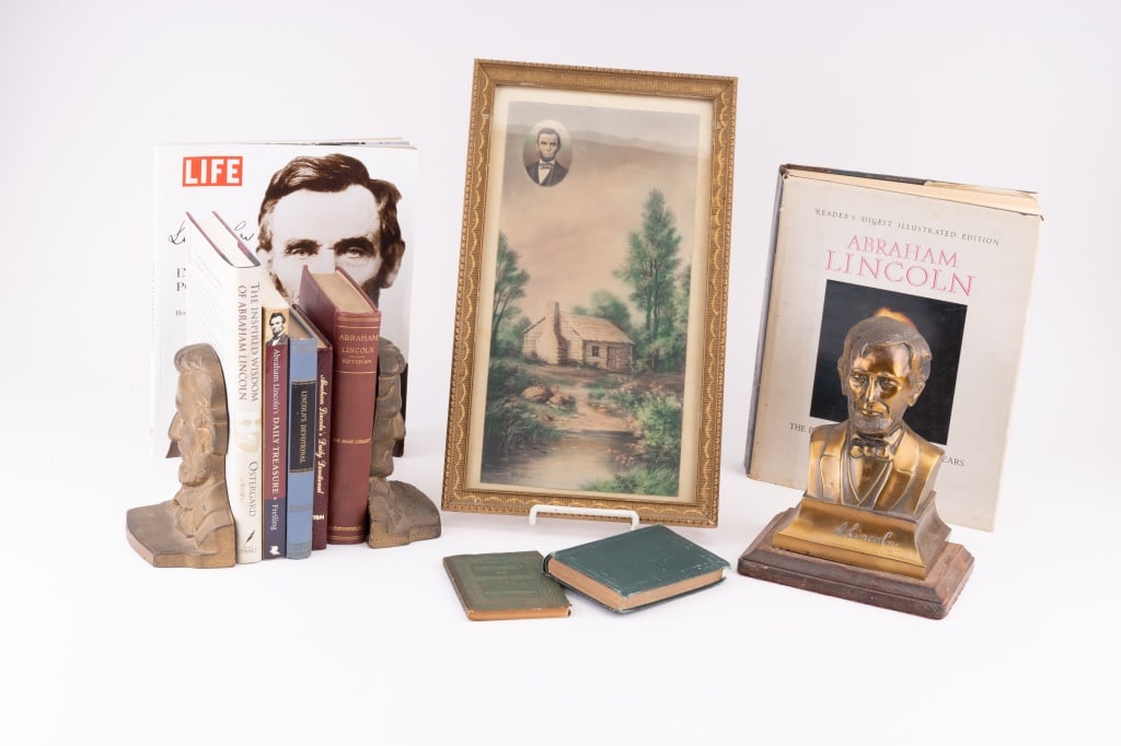 Abraham Lincoln Books, Book Ends & Art: Brass Lincoln bust (approx 8.5" H) , two cast iron book ends (approx 6" H), Art of Lincoln's "Lincoln Log Cabin" that has his portrait in the corner (measures approx 9" x 15" OD) and a number of books