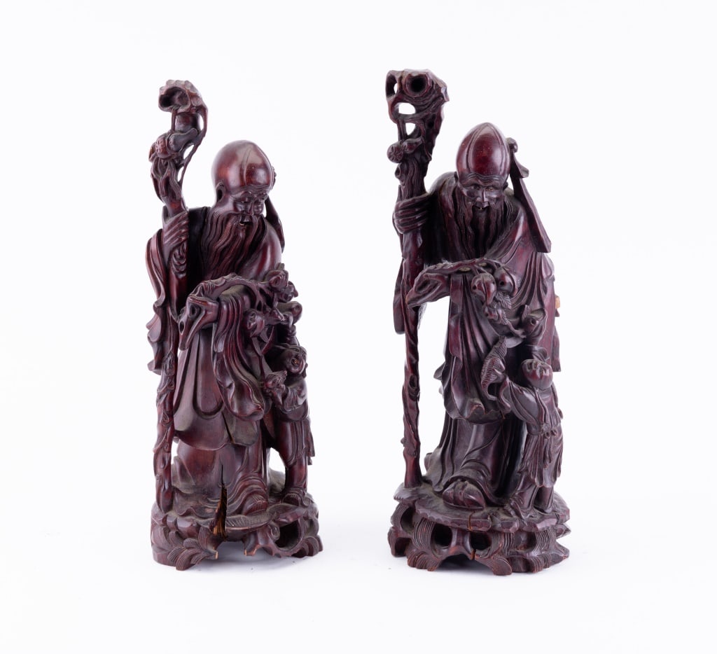 Carved Rosewood Elders (Pair): Each carved from single piece of wood, some shrinkage cracks, one more prominent than the other. Subject is an Elder with a walking stick and a student at their sleeve.