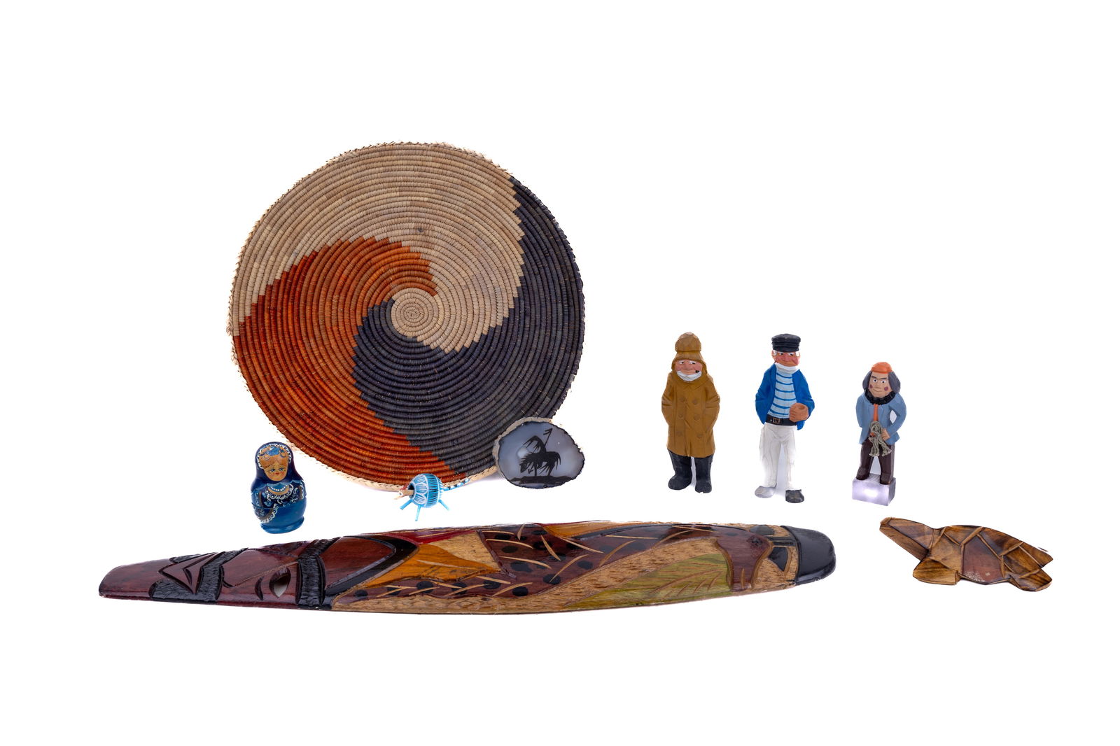 Wooden Travel Collectibles: African mask totem, wooden turtle from Fiji, nesting dolls, Native American agate slice, African basket, Old Salt, and other figurines.