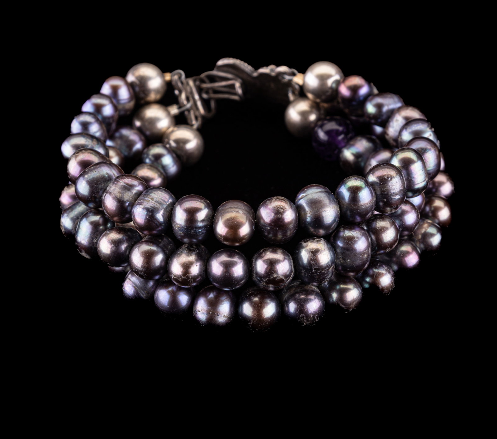 Triple Strand Pearl Bracelet: Approx 7" bracelet with decorative but unmarked clasp likely silver, unmarked sterling possibly from India like consignor. Pearl colors gray to blue with one purple semi-precious bead.
