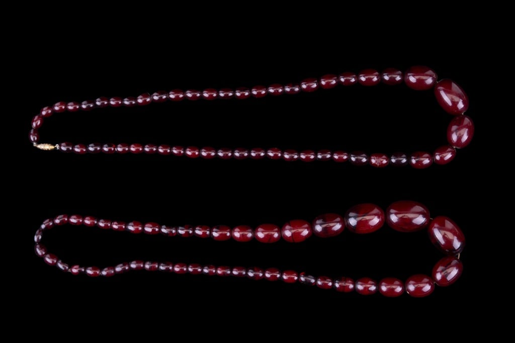 Amber & Bakelite Necklaces: Cherry-colored bakelite necklaces. Both approx 29" L. Weight of amber approx 104 grams, the other approx 78 grams.