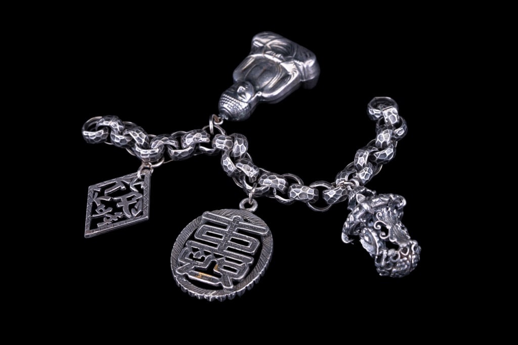 4 Chinese Export Silver Pendants: 4 Chinese export silver (unmarked but tests for silver) pendants depicting seated scholar / Buddha, lantern, and two with symbols on a linked chain. Largest approx 1.5" L.