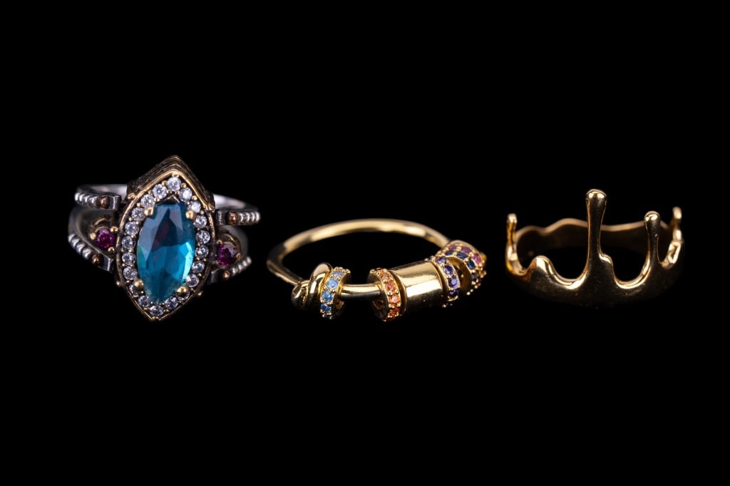 Three Sterling Silver Rings: Three sterling silver rings including a blue to ruby red hue pave cz, flip ring gold tone vermeil crown and small charm style.