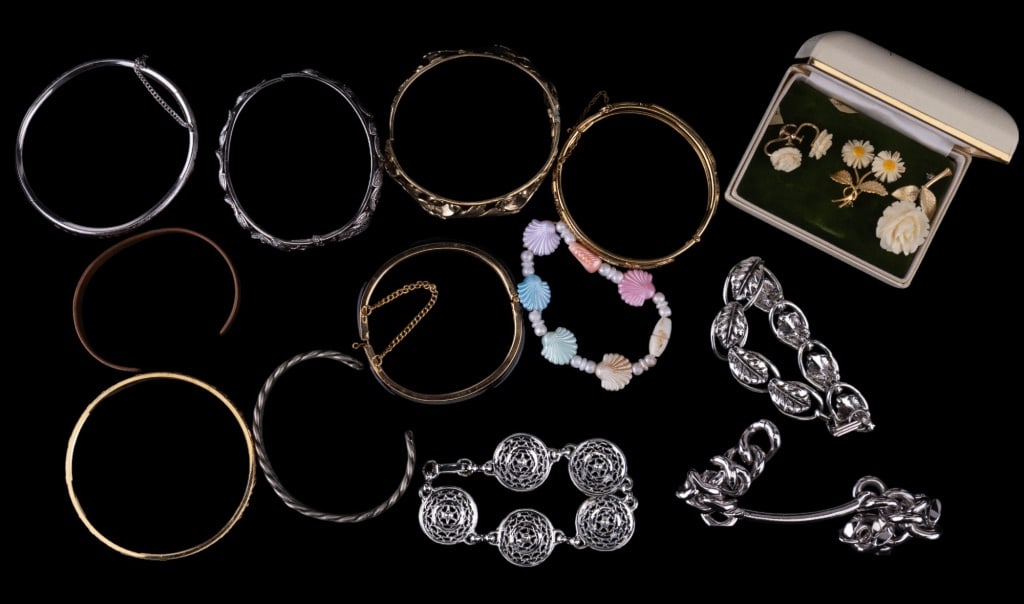 Whiting & Davis, Krementz & More Jewelry: Variety of costume bracelets including Whiting & Davis gold tone repousse hinged bangle, sterling 925 hinged bangle with safety chain and Krementz two brooch and screwback earrings set.