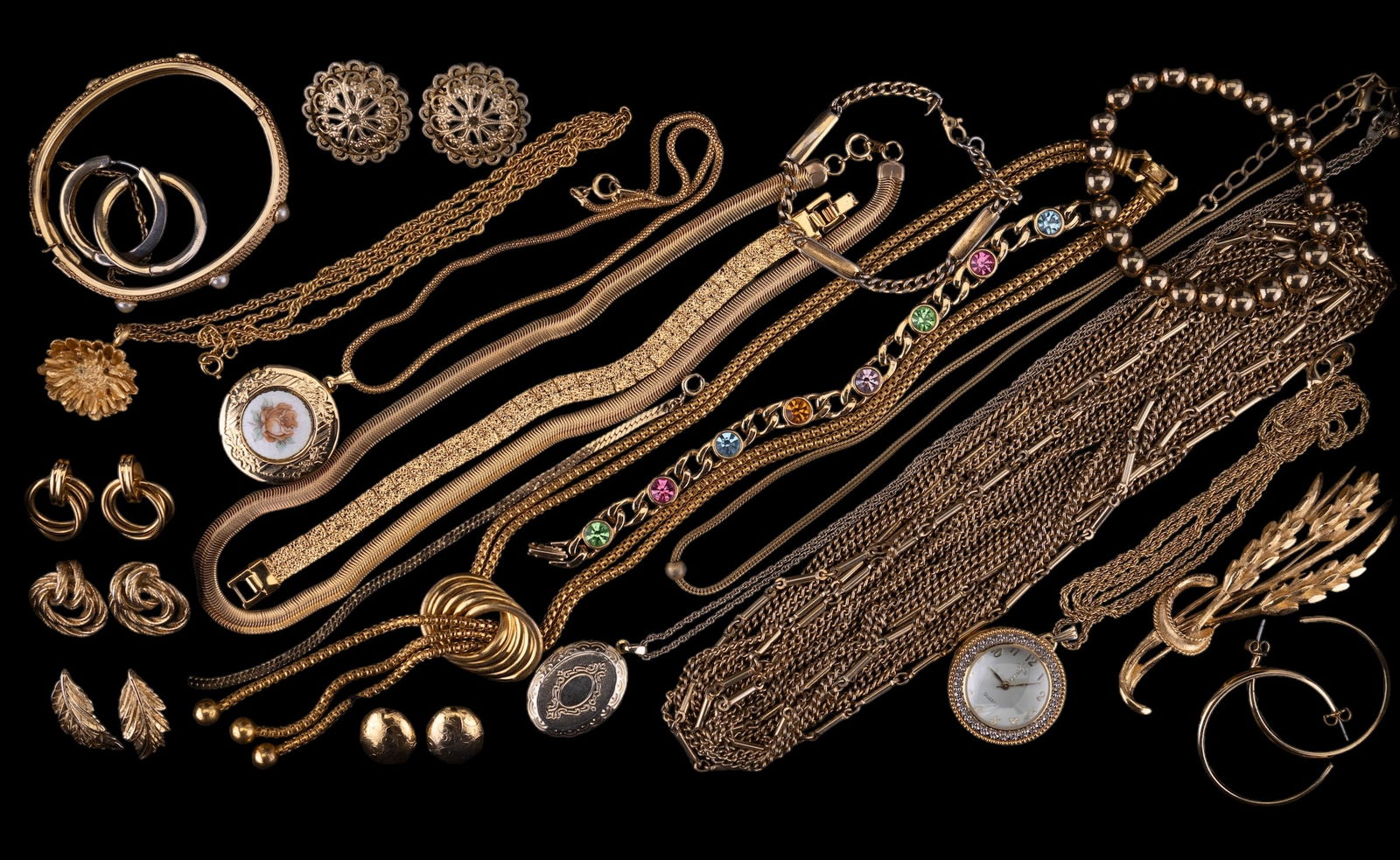 Gold Tone Costume Jewelry: Gold tone costume jewelry featuring a 4" Monet wheat pin, a pair of Monet triple ring drop earrings, a 60" 4 strand necklace, bracelets, necklaces, and earrings. Total of 22 items.