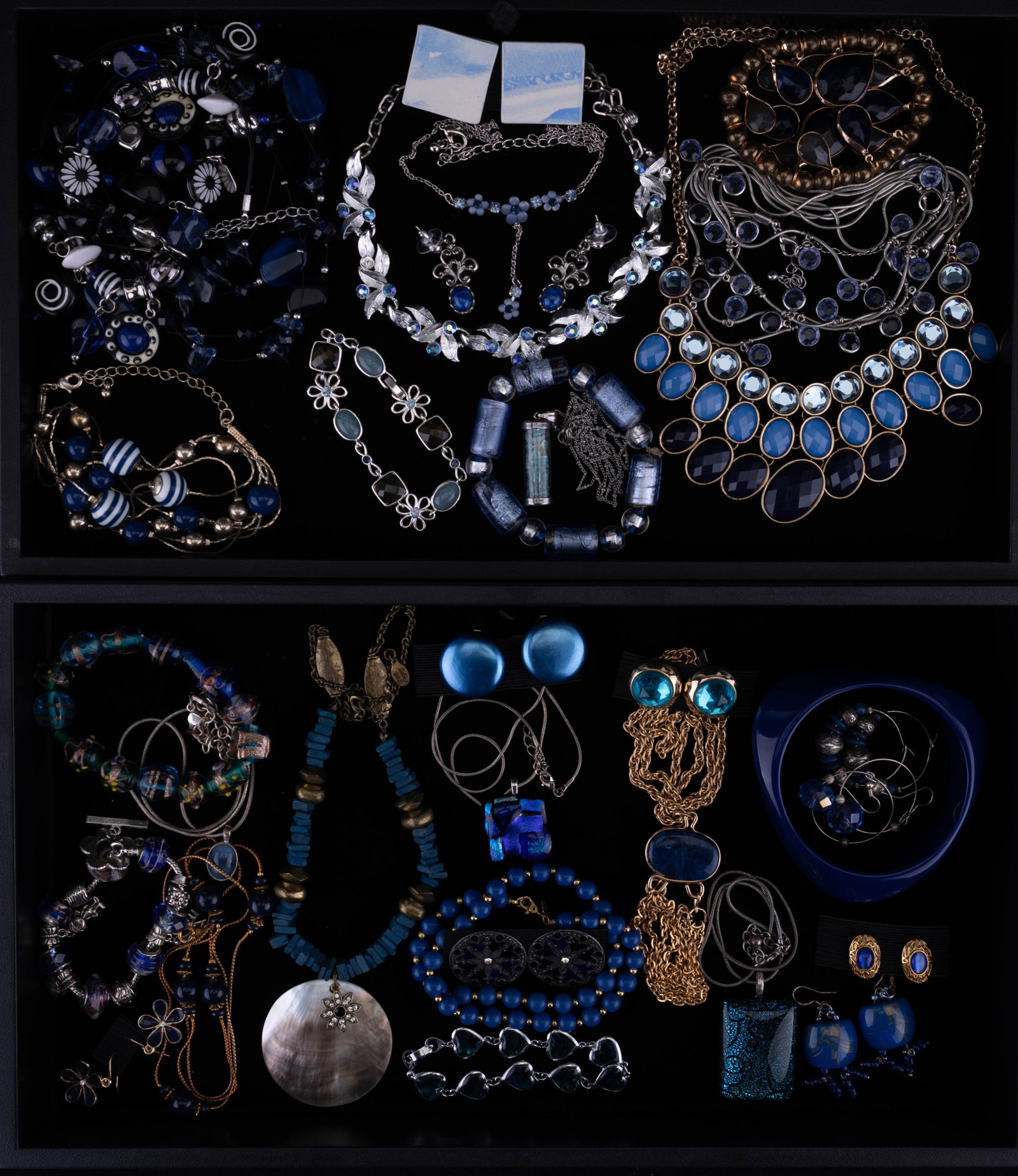 2 Trays of Blue Costume Jewelry: 2 trays of blue costume jewelry featuring a Cookie Lee necklace with MOP pendant, blue disk Japan clip earrings, Sarah Coventry gold tone necklace with blue pendant accent, 16" vintage Monet necklace,