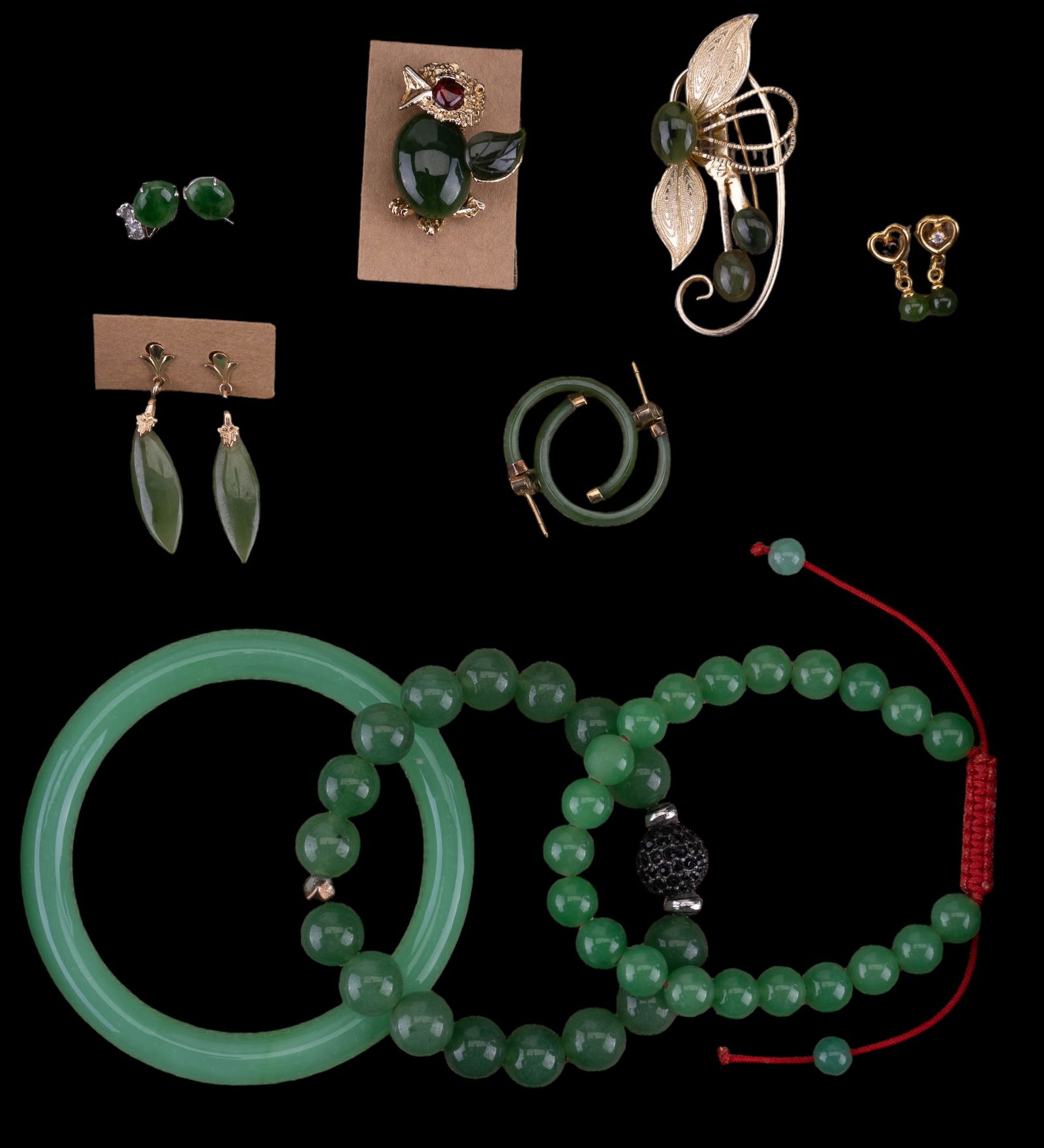 Jade, Nephrite, & Glass Jewelry: Jade, nephrite, and glass jewelry featuring a vintage Swaboda chirping bird pin with jade body/wing and garnet eye, 2 beaded jade bracelets, a solid green glass bracelet/bangle, 4 pairs of pierced ear