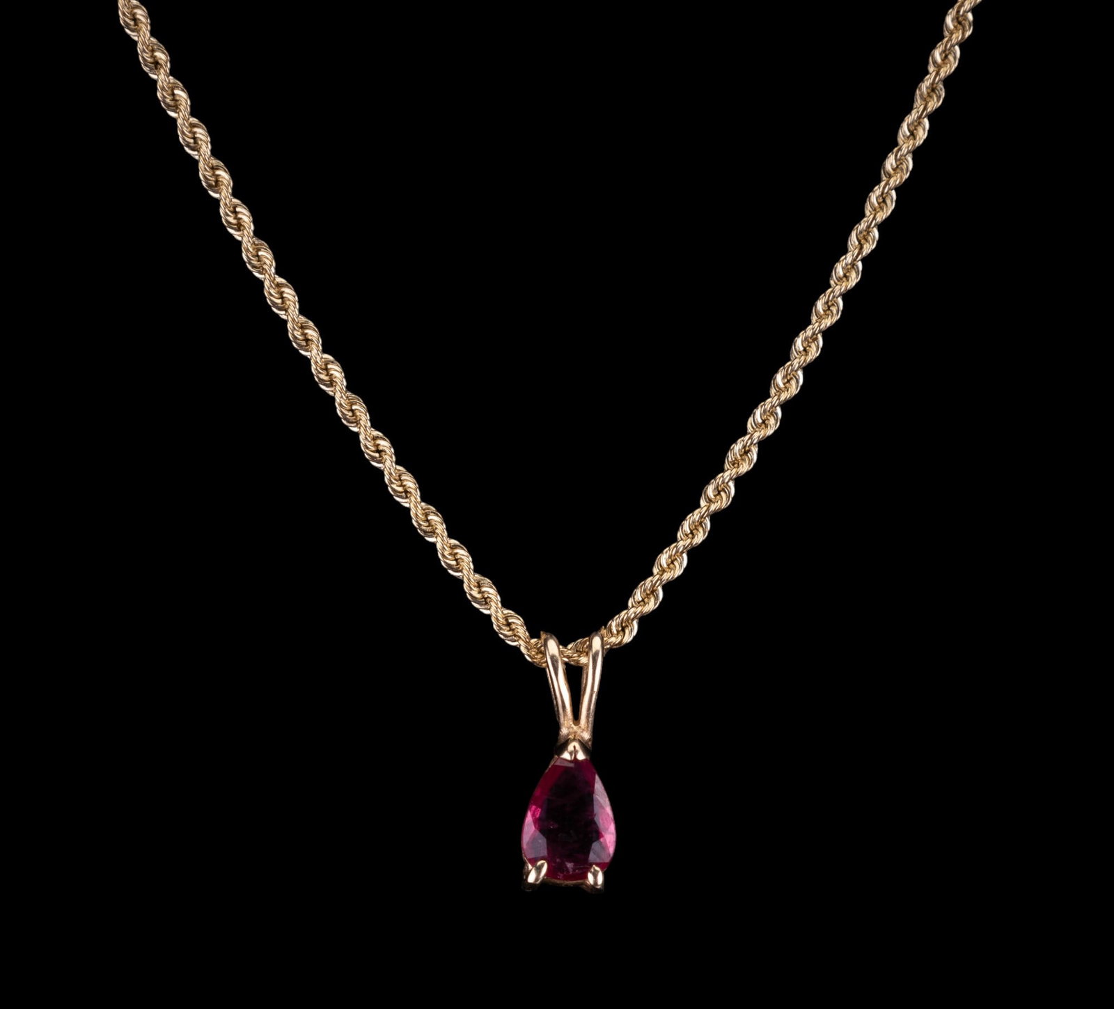 14K Gold Ruby Pendant & Necklace: A 14K gold 1/2" teardrop ruby pendant suspended on a 14K gold 20" rope chain. The ruby is approx. 4x6mm (0.05 carats) with minor inclusions. Pendant and necklace 2.19 DWT.