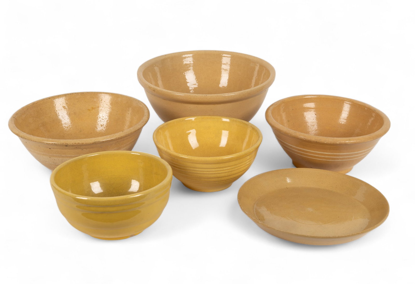 Assorted Yellow Ware Pottery: Yellow ware pottery includes three nesting bowls (largest 12" Dia x 5.25" H). Smallest bowl has hairline crack on side; medium bowl has worn glaze on inside. Two additional bowls and platter. All item