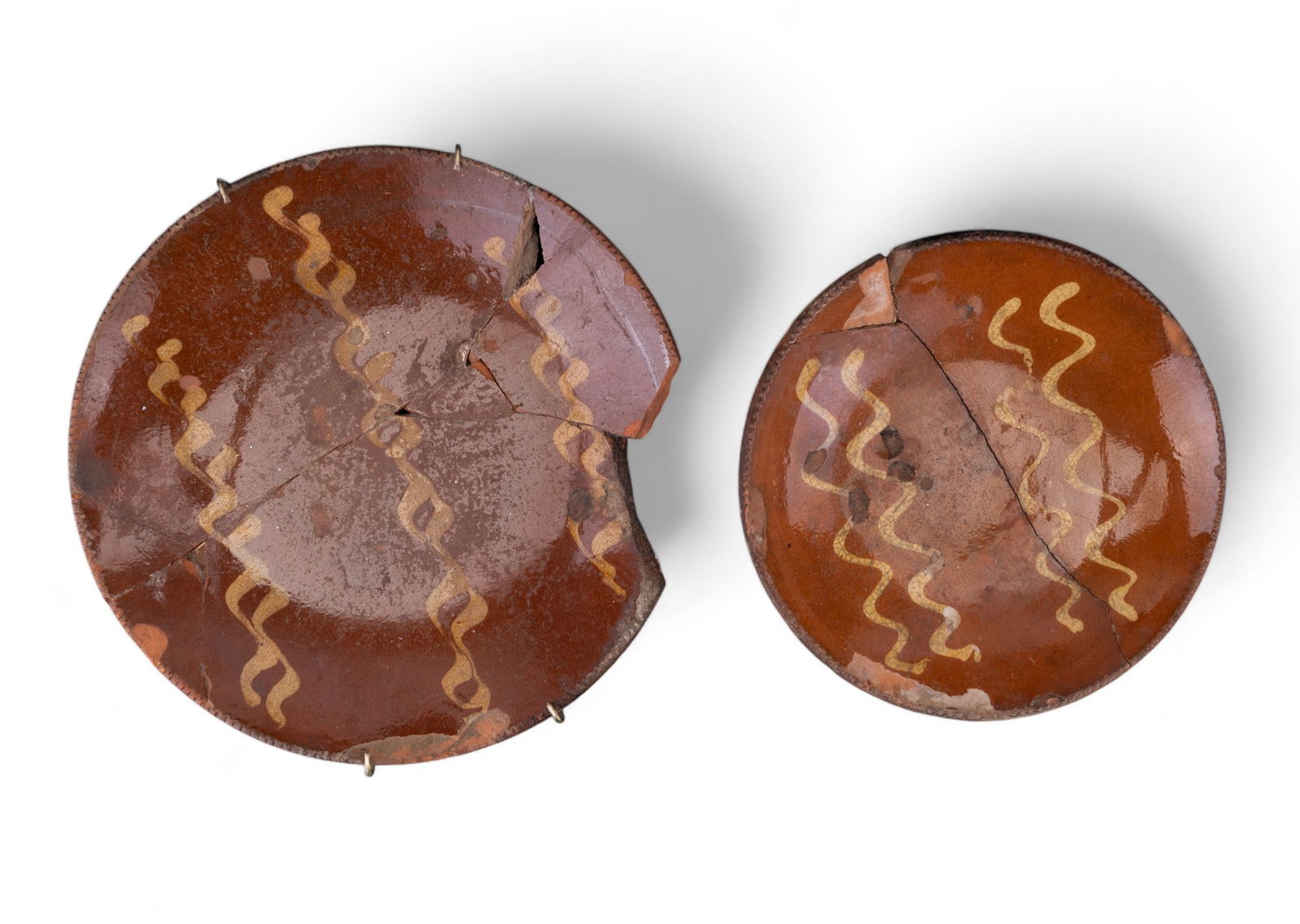 Antique Excavated Slip Decorated Redware: Two pieces of antique slip decorated redware excavated from the Lyster house in Holmdel, NJ by archaeologist Robert Norhterer. Plates measure approx. 9" dia and 11" dia. Pieces recovered have been res