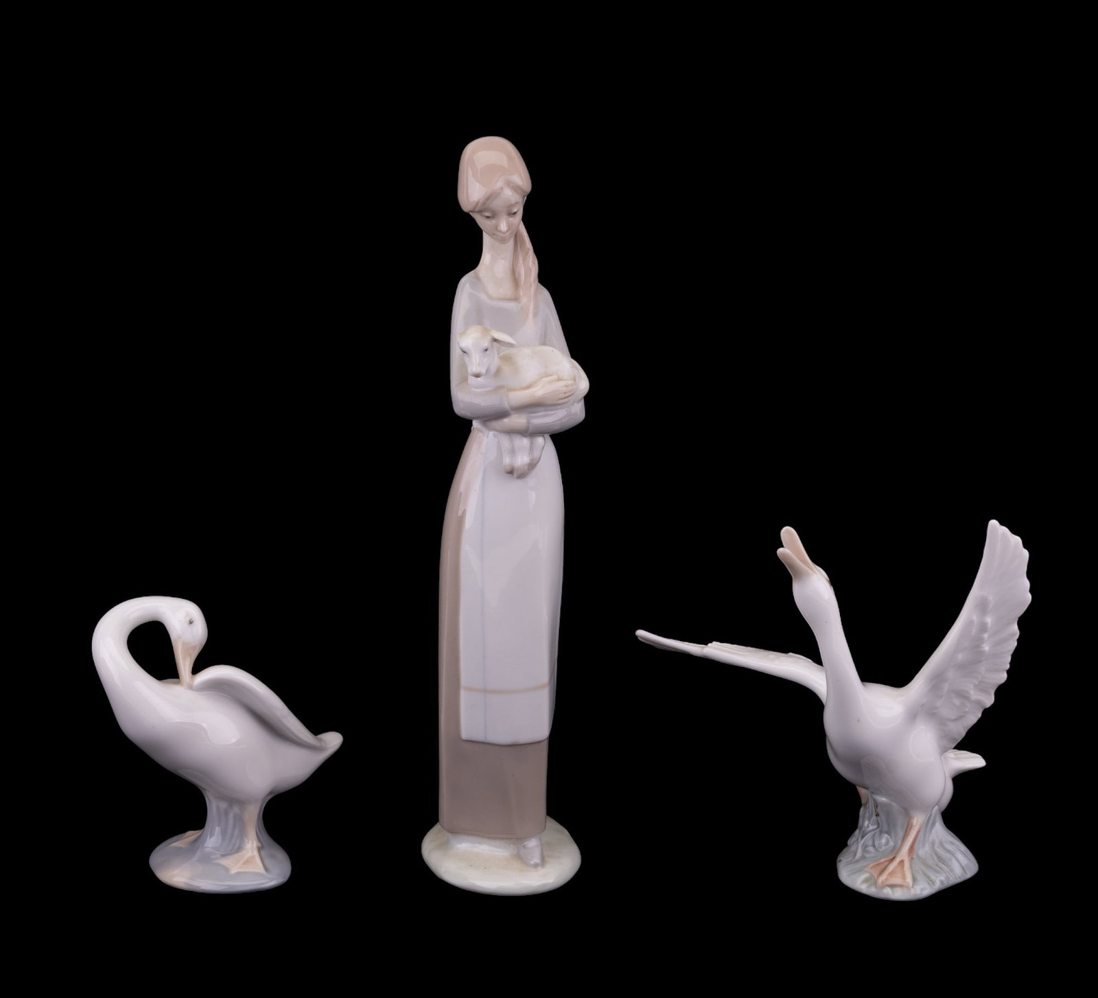 Lladro Swan & Woman Figurine: Lladro figurines including 2 swans and a woman with lamb (measures approx 10.5" H). Note: one ear broke off of lamb.