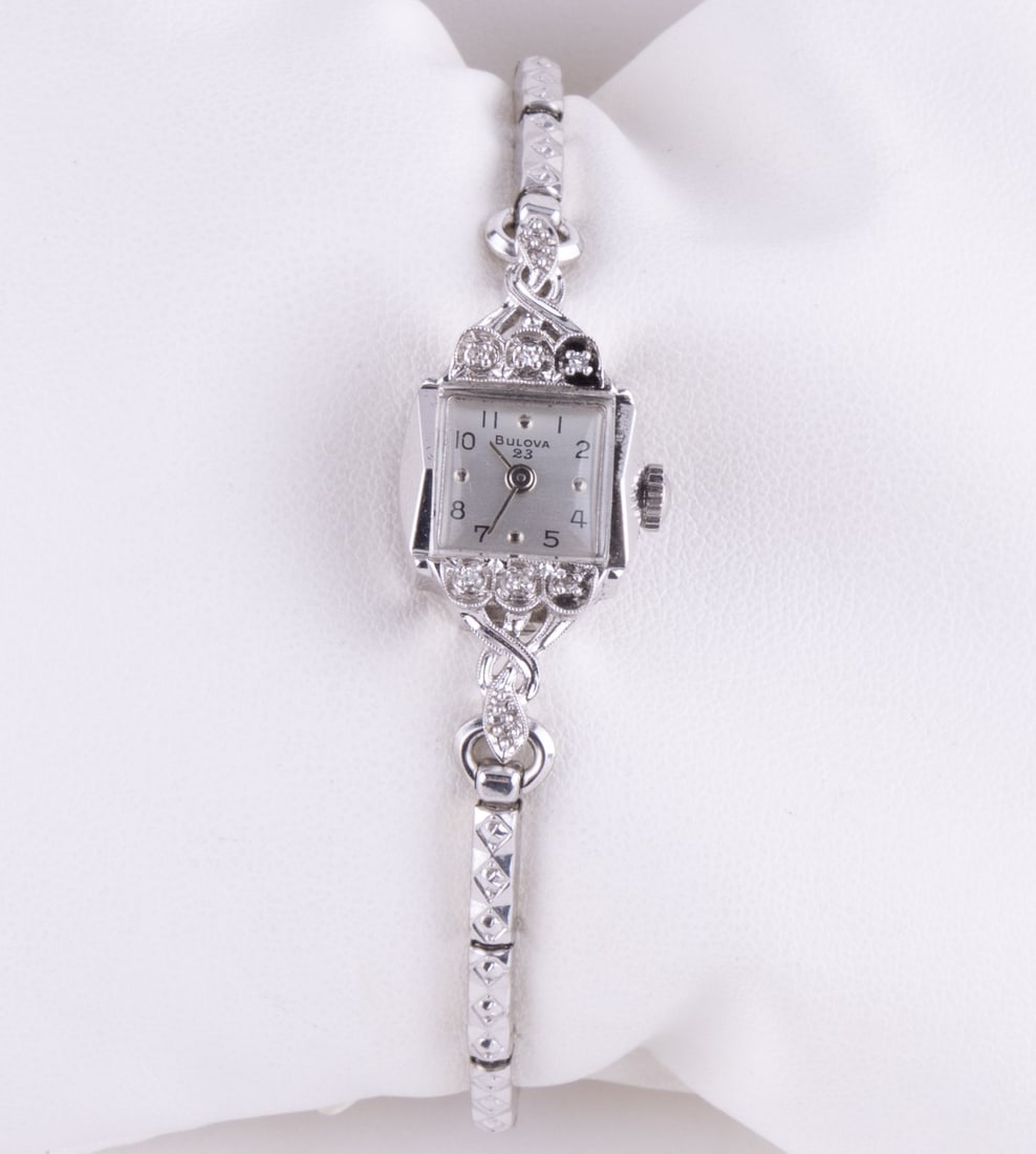Bulova 14K White Gold Diamond Watch: Ladies 14K white gold Bulova wristwatch with 6 diamonds around the face. Reverse marked with numbers 116536. There is a B on the winder. The band is marked Gemex 10k G.F. TOPS. Watch appears to run bu