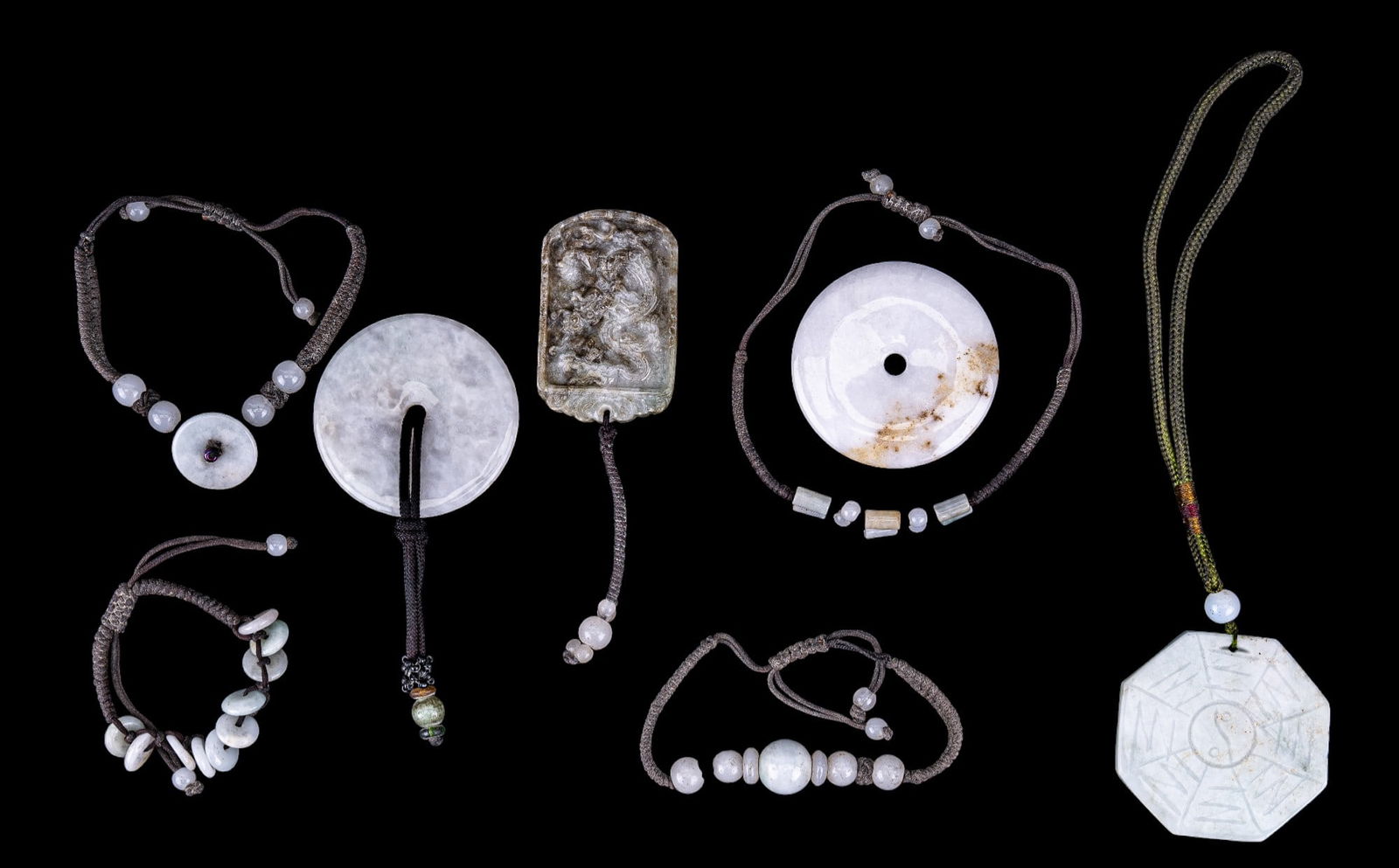 Jadeite Pendants, Bracelets (White): A grouping of white stones that all test for hardness of jadeite. In grouping are four large pendants, and four rope bracelets with stone charms. On bracelets spherical beads do not test for jadeite (