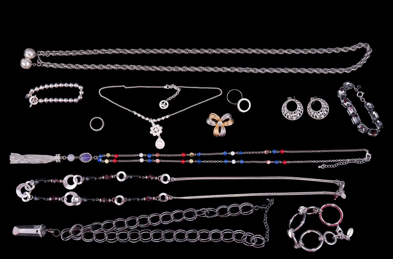 Trifari, Lia Soph. & more Jewelry: Grouping consists of a Loft brand rhinestone bracelet, a Trifari bracelet, a C.J Banks multi colored necklace with tassel pendant, a Lia Sophia purple silvertone bead necklace, a marked silvertone bea