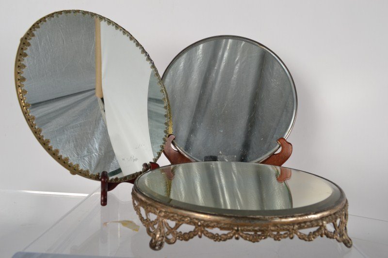 Three Plateaus: Three plateaus; one Edwardian with ornate brass footed base, one on silver plated ball feet with beveled mirror, one large brass-edged with feet