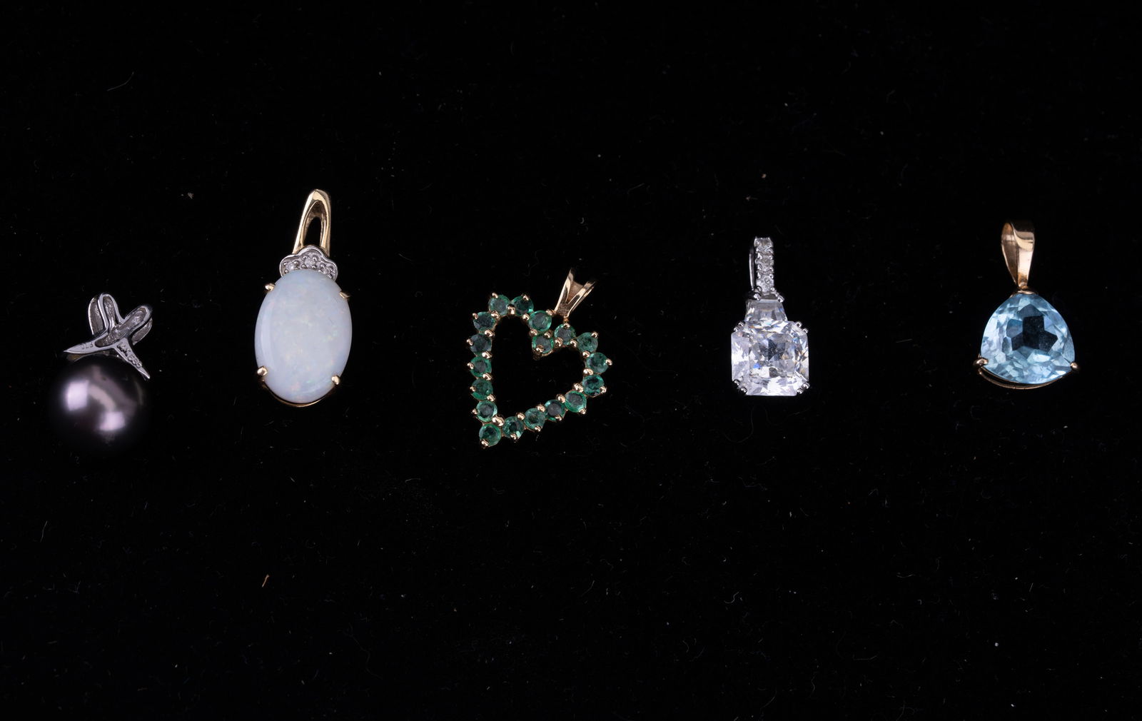 14K Gold Pendants w/ Topaz, Emerald, Opal (5): Five 14K gold pendants with various stones. Consists of a white 14K gold pendant with faceted glass, a 14K yellow gold pendant with triangular faceted blue topaz, a 14K gold heart pendant with emerald