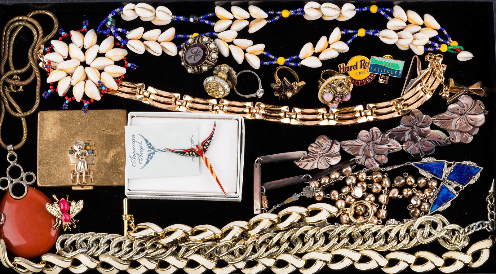 Costume Jewelry: Includes a variation of necklaces, brooches, rings and more. There are gold tone and shell necklaces, one necklace with orange pendant marked Made in West Germany, vintage compact, Lavaggi American An