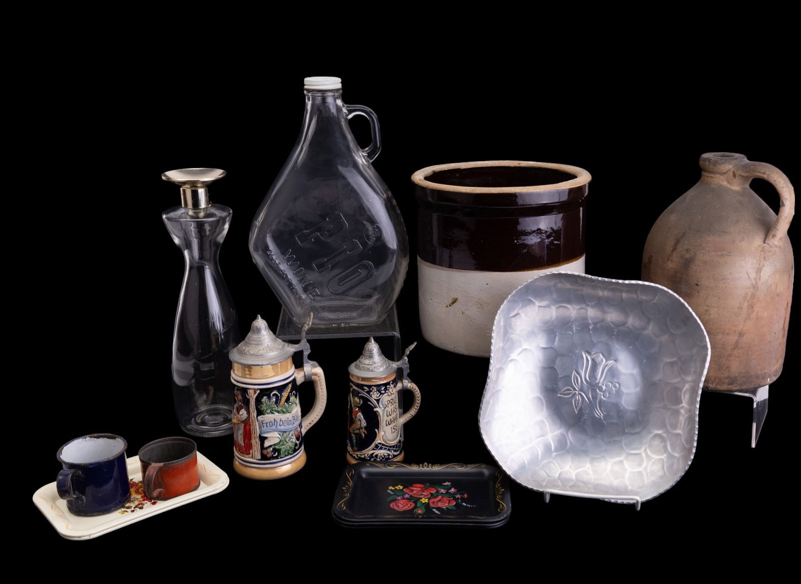Antique & Vintage Crocks, Steins, Bottles, Tinware: Lot consists of one brown/white one gallon crock, a stoneware 1 gallon jug with some chips, two German beer steins, two tin painted & blue enameled children's cups, 5 Tole painted trays, Buenilum hamm