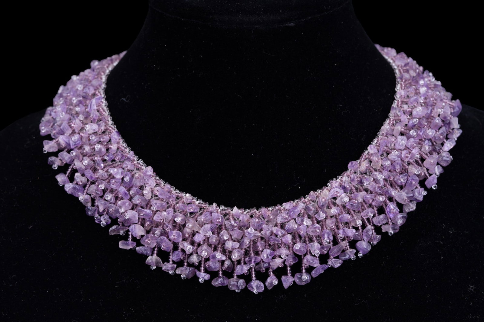 Chunk Amethyst Bead Lace Necklace: A chunk amethyst bead lace necklace measuring approx. 16.5" end to end with a textured circular clasp. Measures approx. 1.5" wide at thickest point.