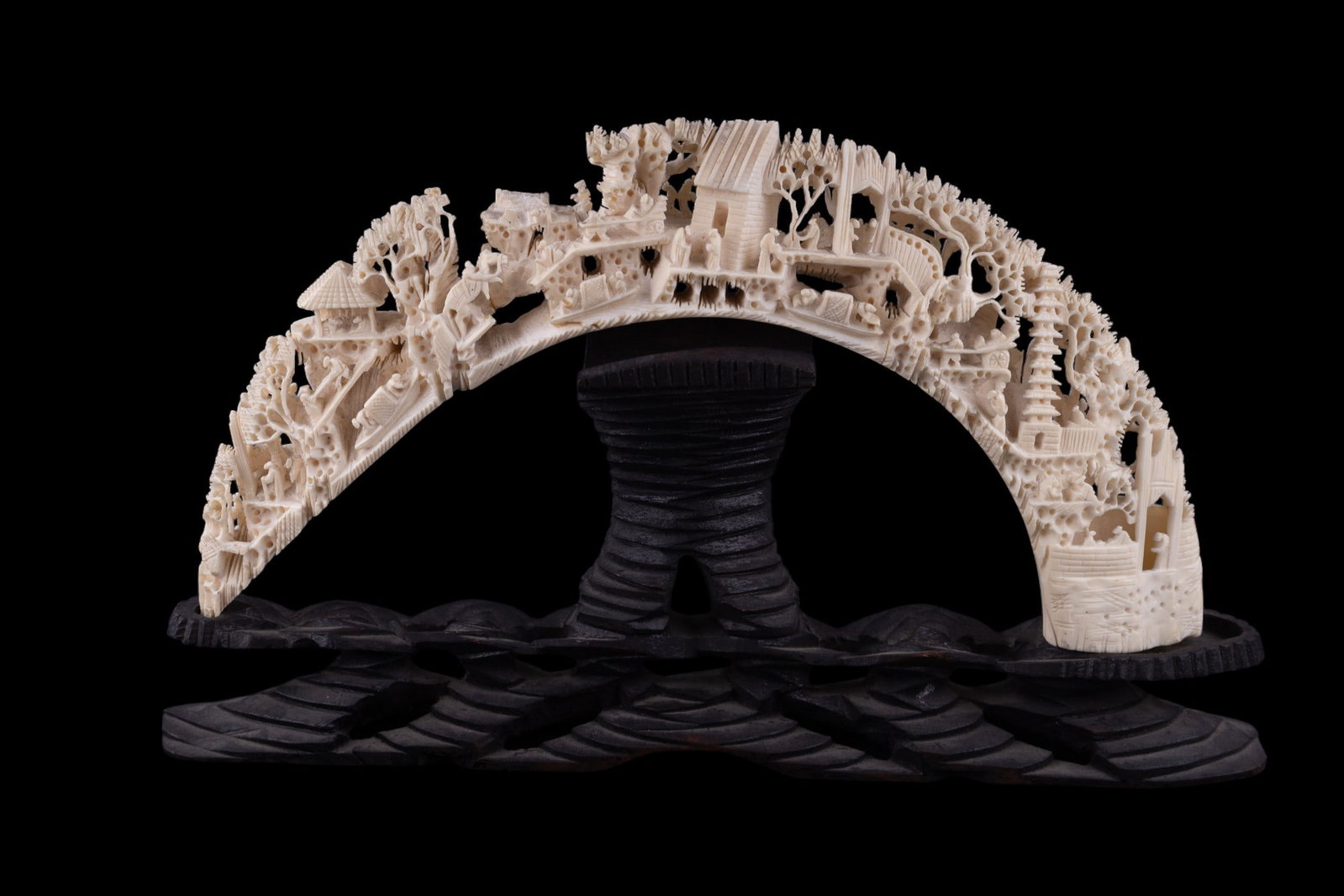 Asian Tusk-Shape Carved Village Scene: Finely-carved Asian village scene on a bone/natural material tusk w/ carved wood stand. There is some previous repair to tusk visible on the bottom. Due to improper repair, the curve of the sculpture 