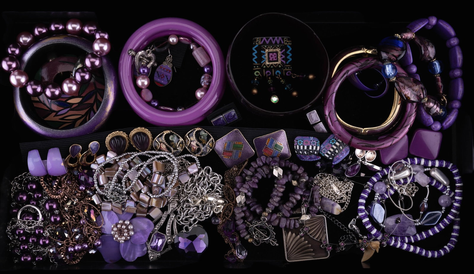Costume Jewelry Purple Theme: A tray of purple colored costume jewelry including 11 necklaces, 10 bracelets, 14 pairs of earrings (pierced and clip), and 1 pin. Some wear due to use.