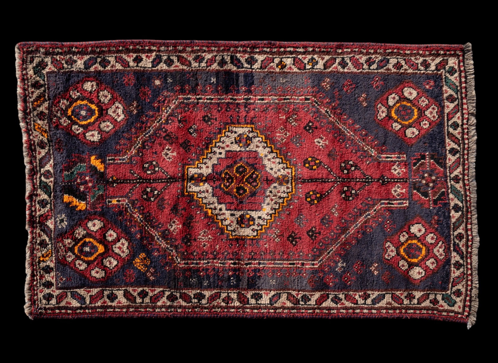 Persian Tribal Rug: Persian tribal rug approx. 5' x 7'8" w/ red, navy blue, orange, green, brown, black, & tan patterns w/ geometric & floral motifs. *All rugs / carpets are used & come from fine estates. Keystone Auctio