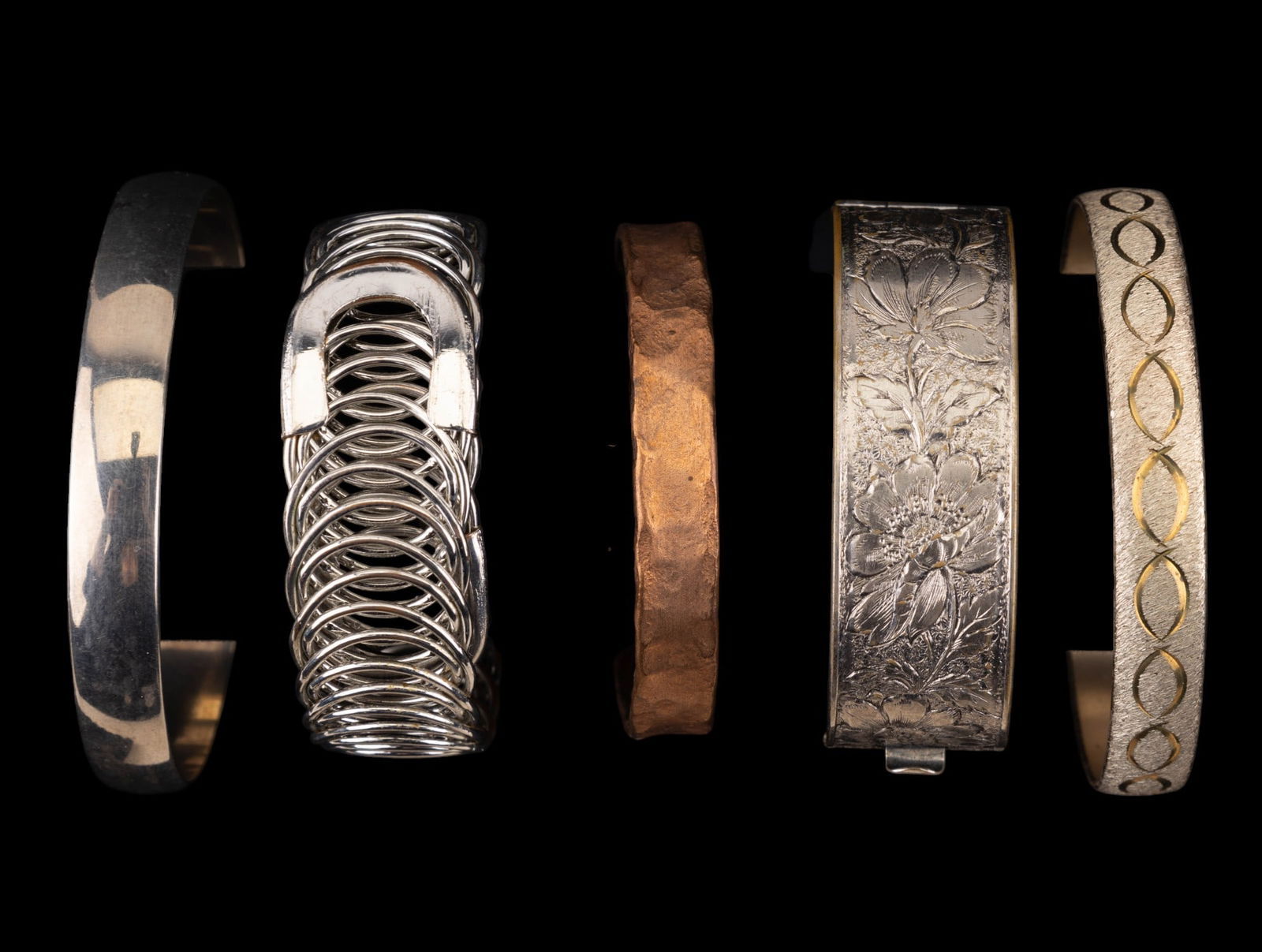 Cuff and Bangle Bracelets: An assortment of bangle and cuff bracelets, five silver tone bangles, some with etched details, and one hammered copper tone cuff bracelet.