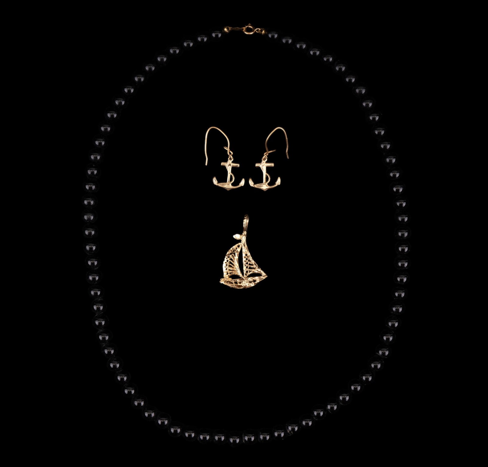 14K Gold Anchor Earrings, Black Onyx Necklace: 14K Gold Anchor Earrings with 1" drop, 1g, onyx bead necklace 18" with 14K gold clasp, and unmarked gold tone sailboat pendant.