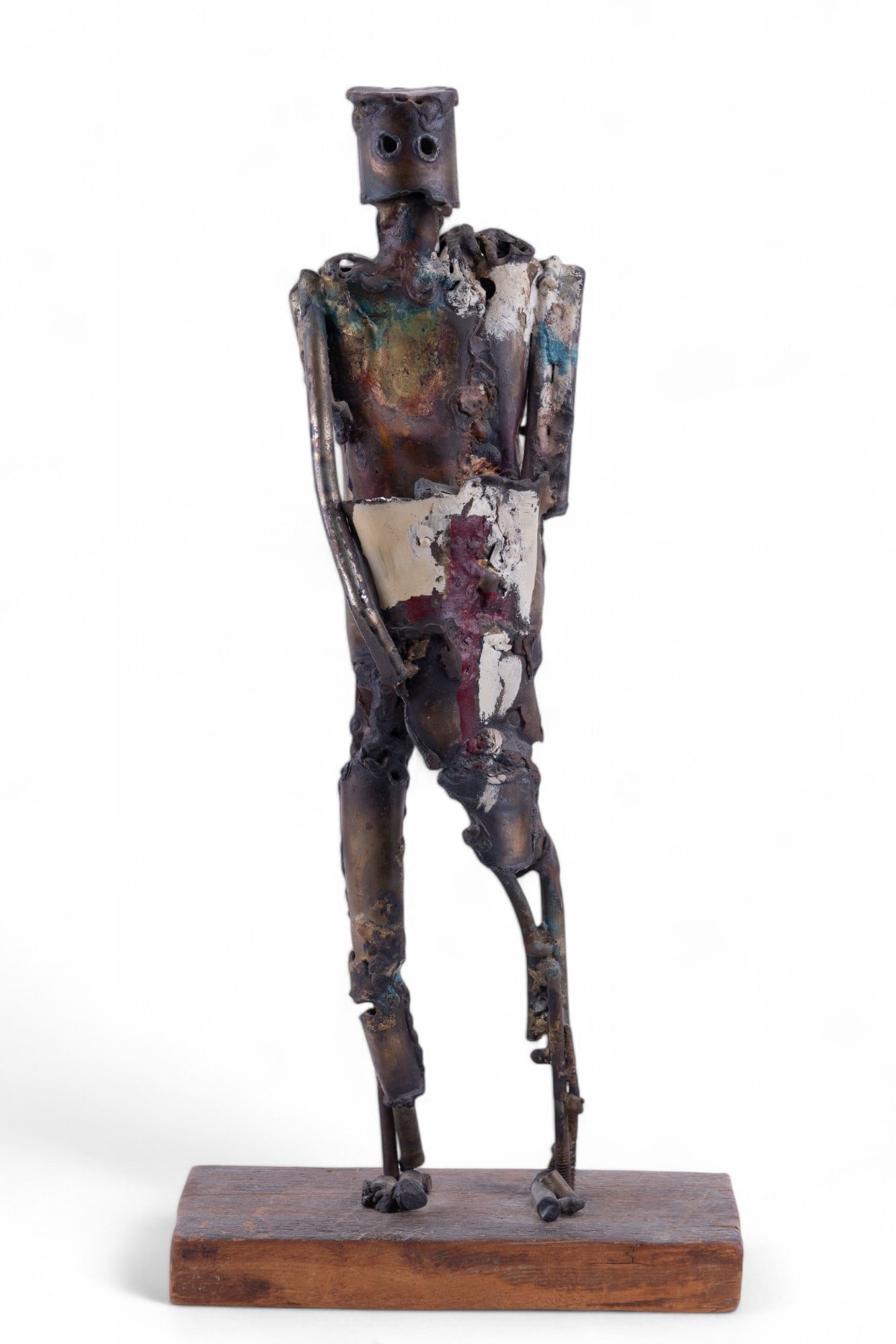 Welded Metal Figural Folk Art Sculpture: Welded metal folk art sculpture of figure with cylindrical helmet and shield with hand painted designs and accents on rustic wood plank base. Measures approx. 18.75" H.