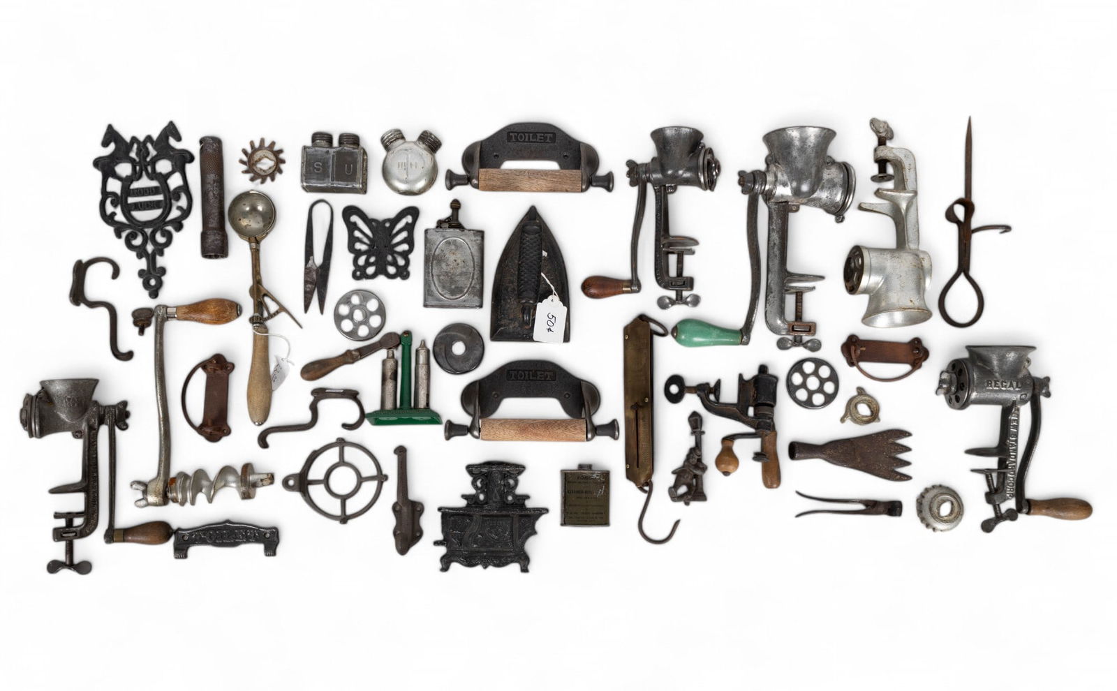 Iron Trivets and Meat Grinders: A collection of decorative iron trivets, sad irons, wall hooks, drawer pulls, and vise mounted meat grinders with brands such as Rollman, Royal, and Universal.