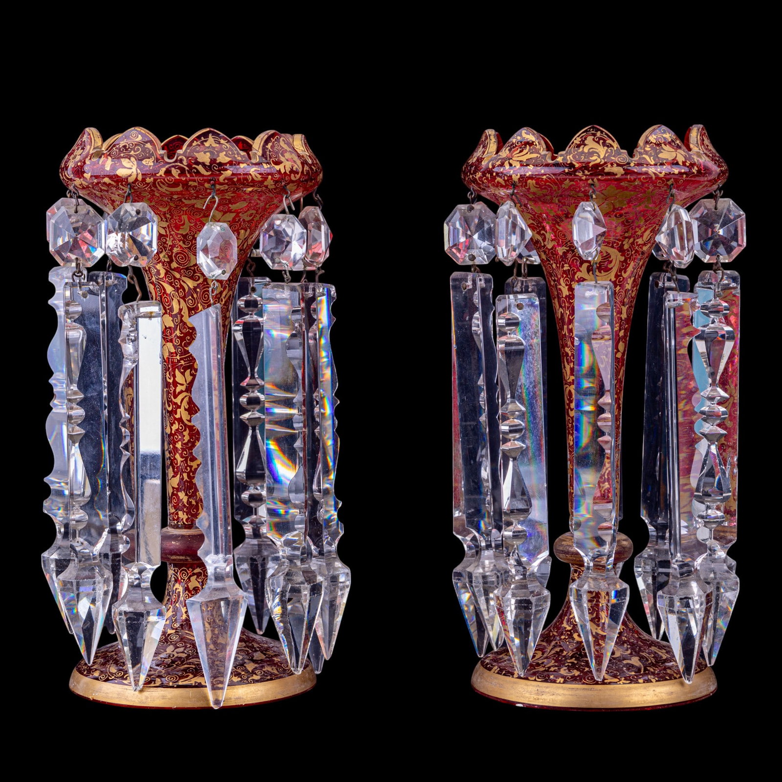 Pr 19th C Moser Bohemian Glass Vases w/ Lusters: Pair of 19th C Moser Bohemian glass flower vases w/ lusters, measuring approx. 10.25" tall & 5" in diameter. Glass is cranberry-colored w/ highly-decorative gilded accents. Vases have heavy crystal lu