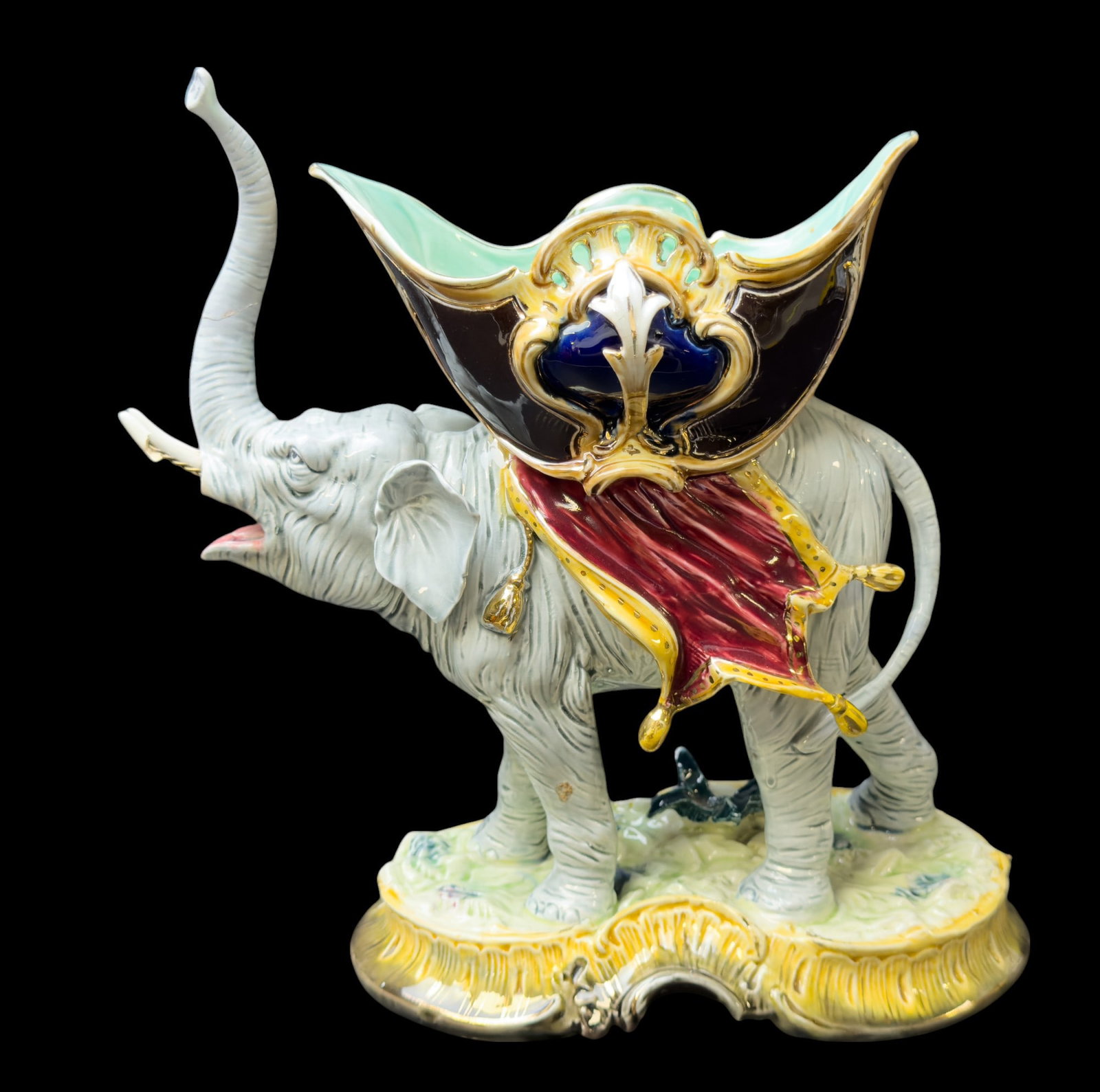 Majolica Elephant approx 10" H: Majolica elephant approx. 10" tall & 11" wide w/ some damage to tusks. Elephant is in a blue-gray color & carries a decorative compote on its back.