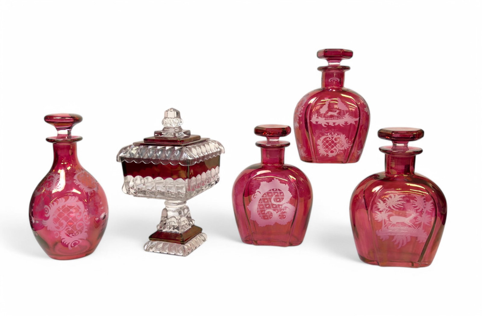 3 Matching Decanters, 1 Similar, & Later Compote: Cranberry etched to clear matching decanters (3), 1 similar decanter, & a later compote w/ lid. Largest decanter is approx. 9.5" tall. Decanters feature several etched designs.