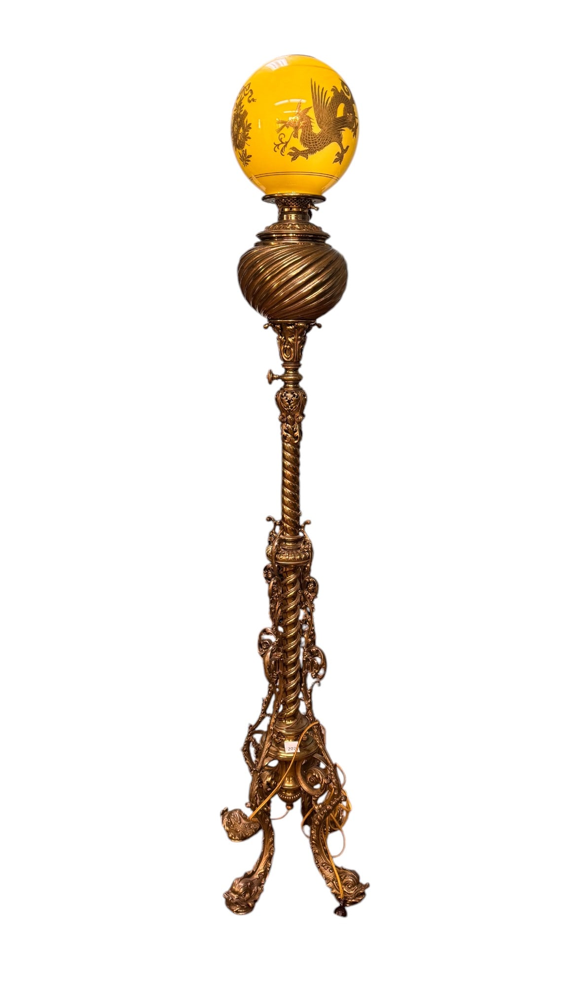 Ornate Brass Parlor Lamp w/ Dragon Shade: Ornate brass parlor lamp w/ yellow globe shade that features 4-clawed dragons & wreaths w/ arrow holder. Lamp body features acanthus details & dolphin/fish feet. Item measures approx. 63" to top of gl